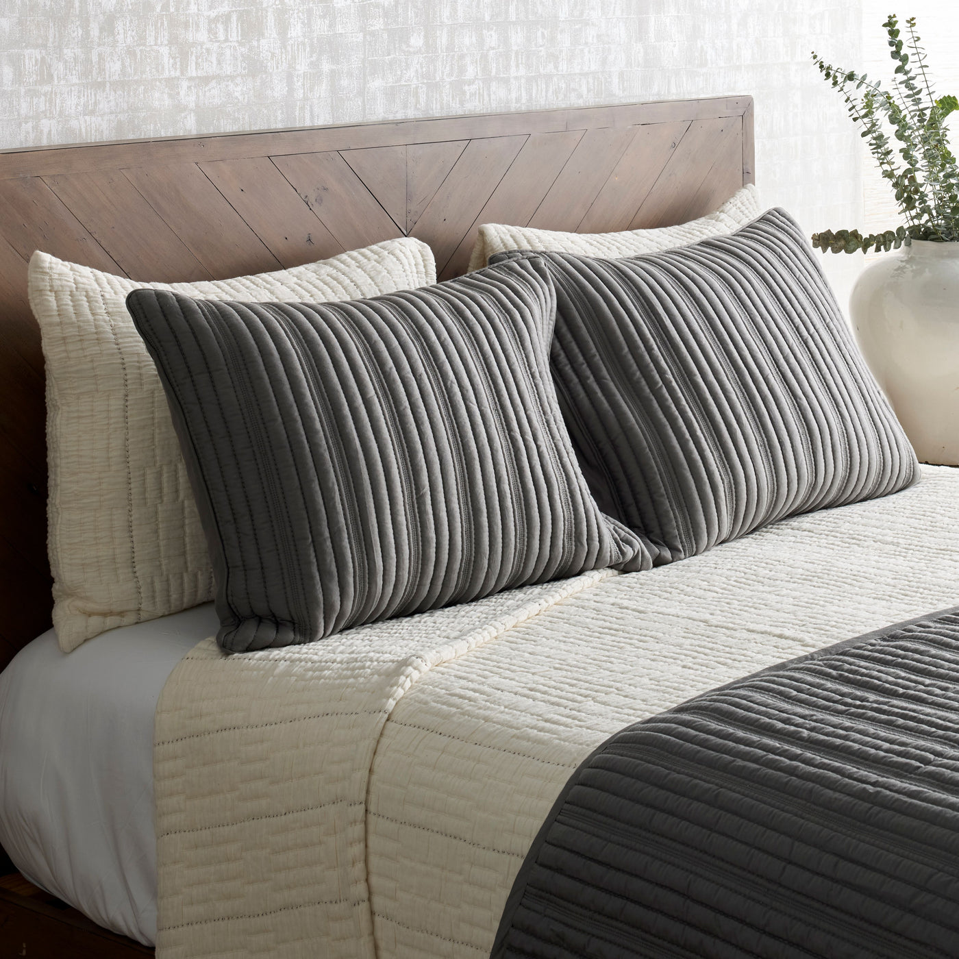Close-up of Ann Gish Pickstitch coverlet set in ivory and charcoal on a styled bed.