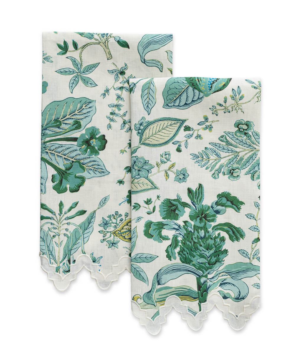 Two folded Matouk Pomegranate linen guest towels with green and blue floral print and scalloped lace edges are displayed on a plain background.