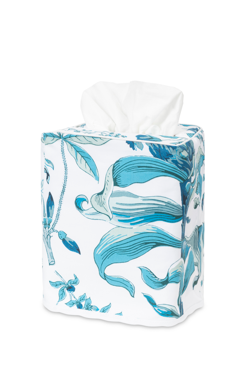 The Matouk Pomegranate Tissue Box Cover features a white and blue floral pattern, resembling fine bedding, with one tissue partially pulled out.