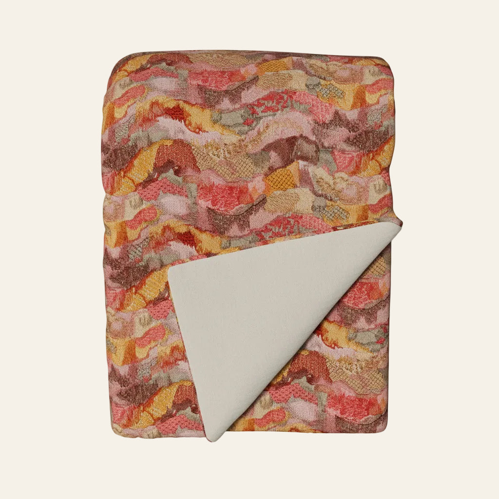 Ann Gish Positano throw in coral and amber wave pattern, ivory reverse, folded flat.