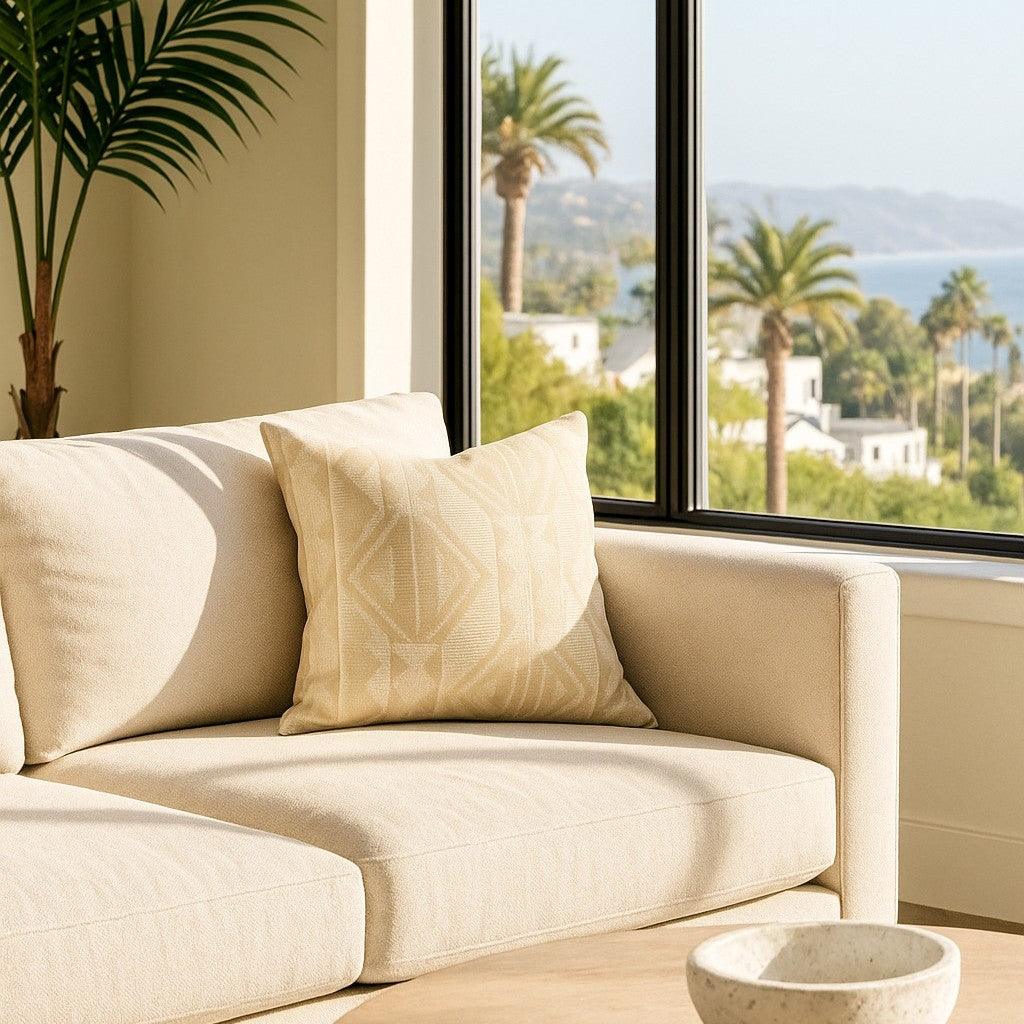 Ann Gish Prestige pillow in ivory with geometric diamond pattern, styled on cream sofa.