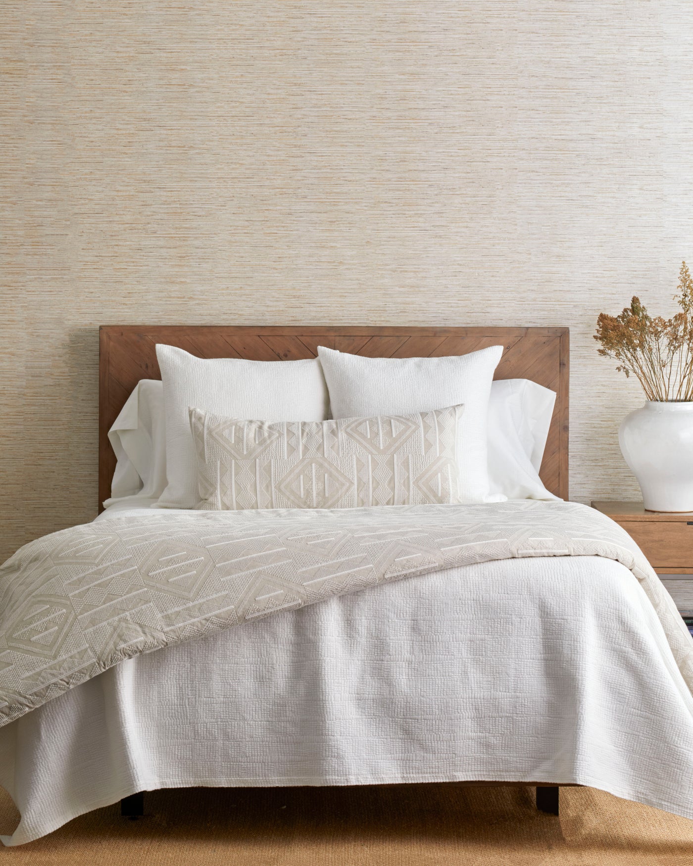 Geometric tufted ivory lumbar pillow styled on a neutral linen bed.
