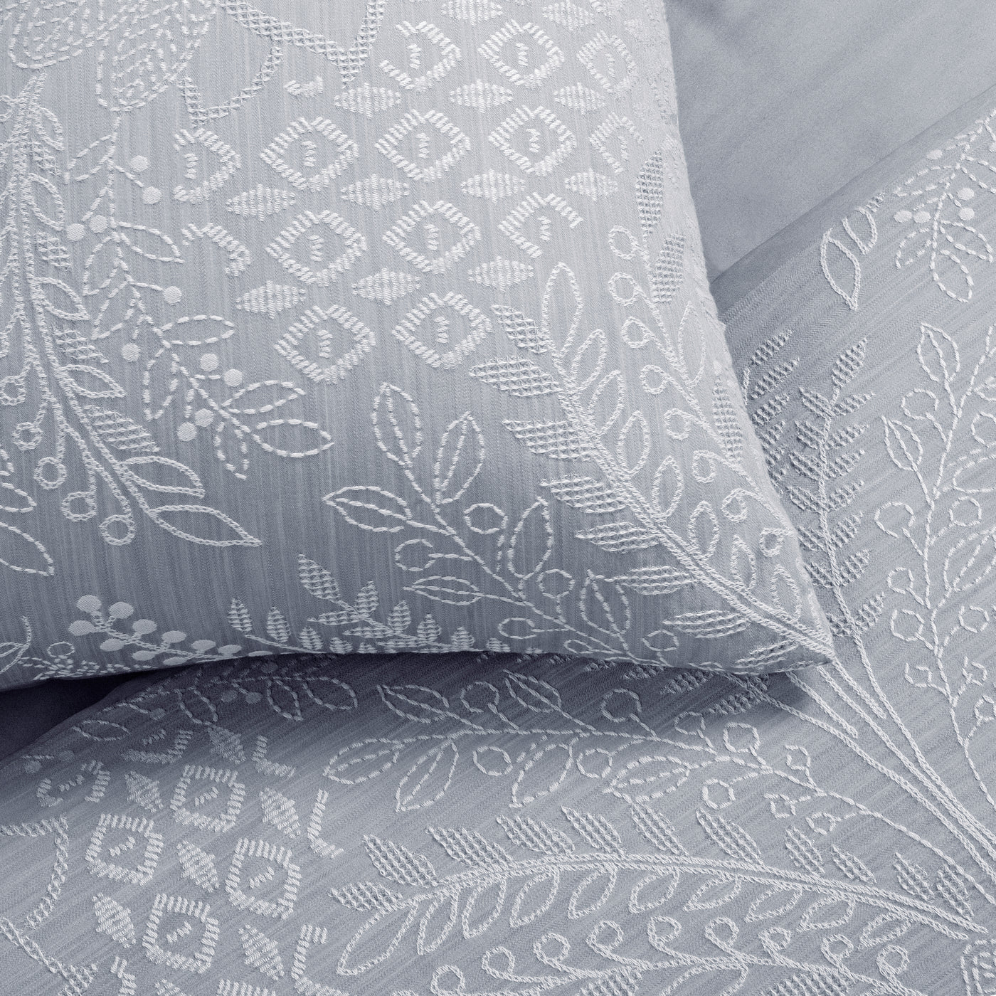 Close-up of Ann Gish Printemps silver pillowcase with white floral embroidery detail.