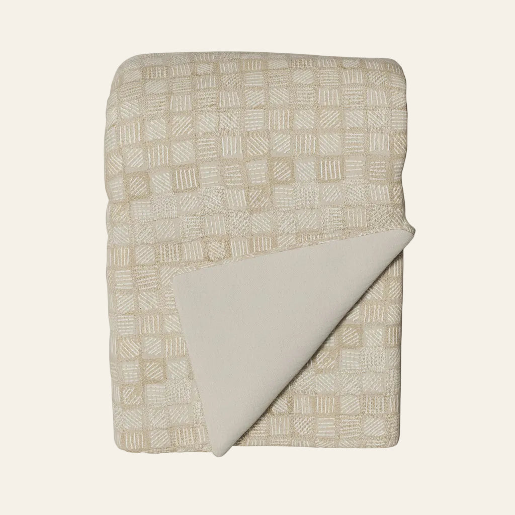 Ann Gish Qasaba throw in ivory and sand, folded to reveal plain reverse.