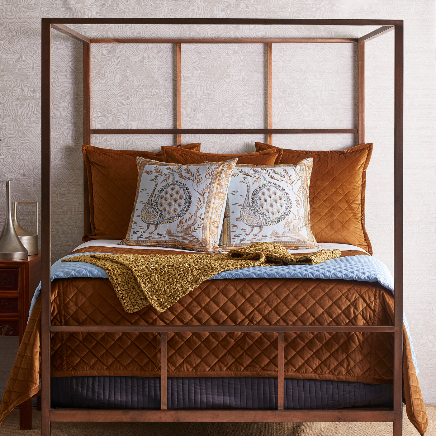 Rust velvet quilted coverlet on four-poster bed with coordinating shams and throw.