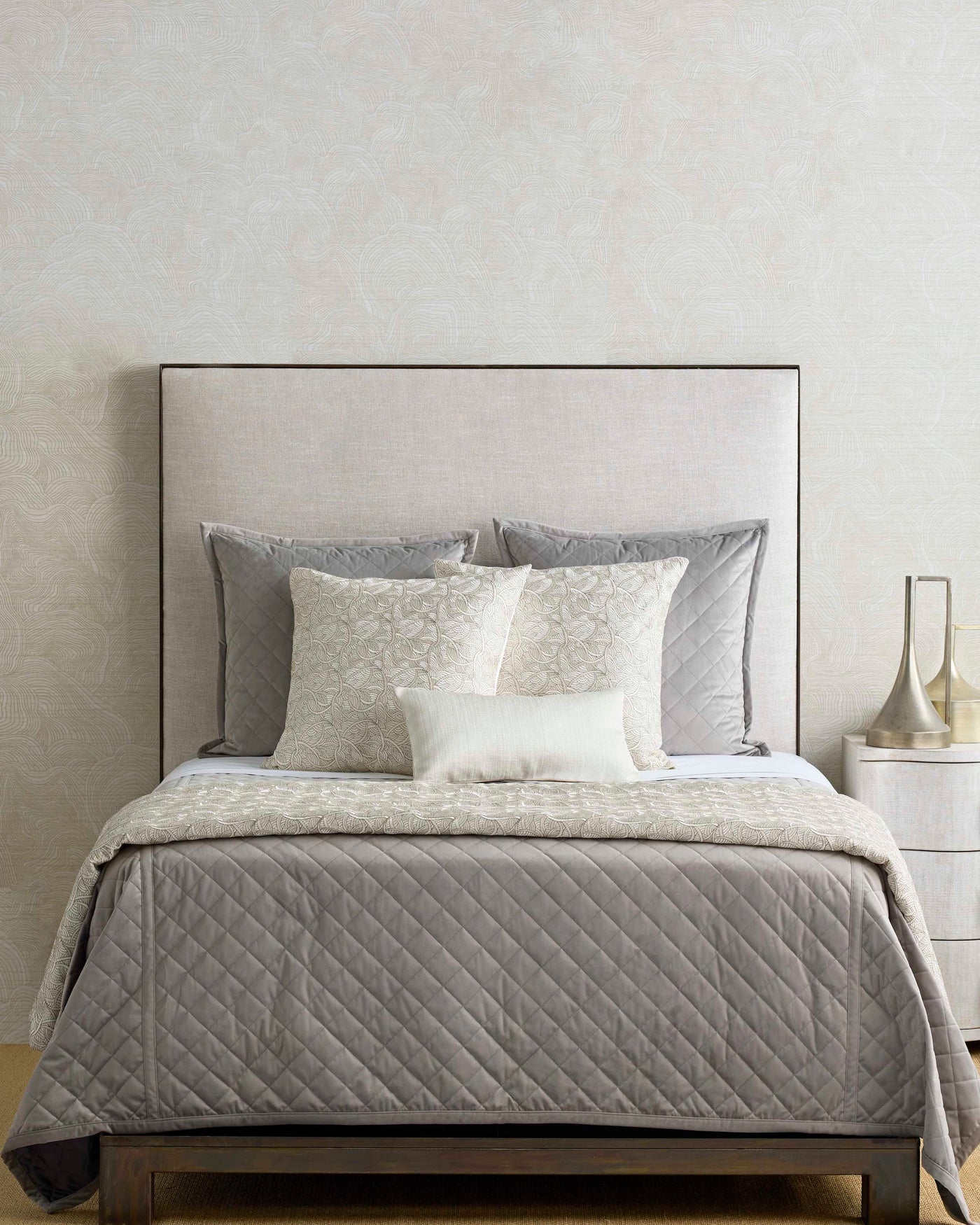 Taupe diamond-quilted velvet coverlet styled on a bed with layered ivory and grey pillows.