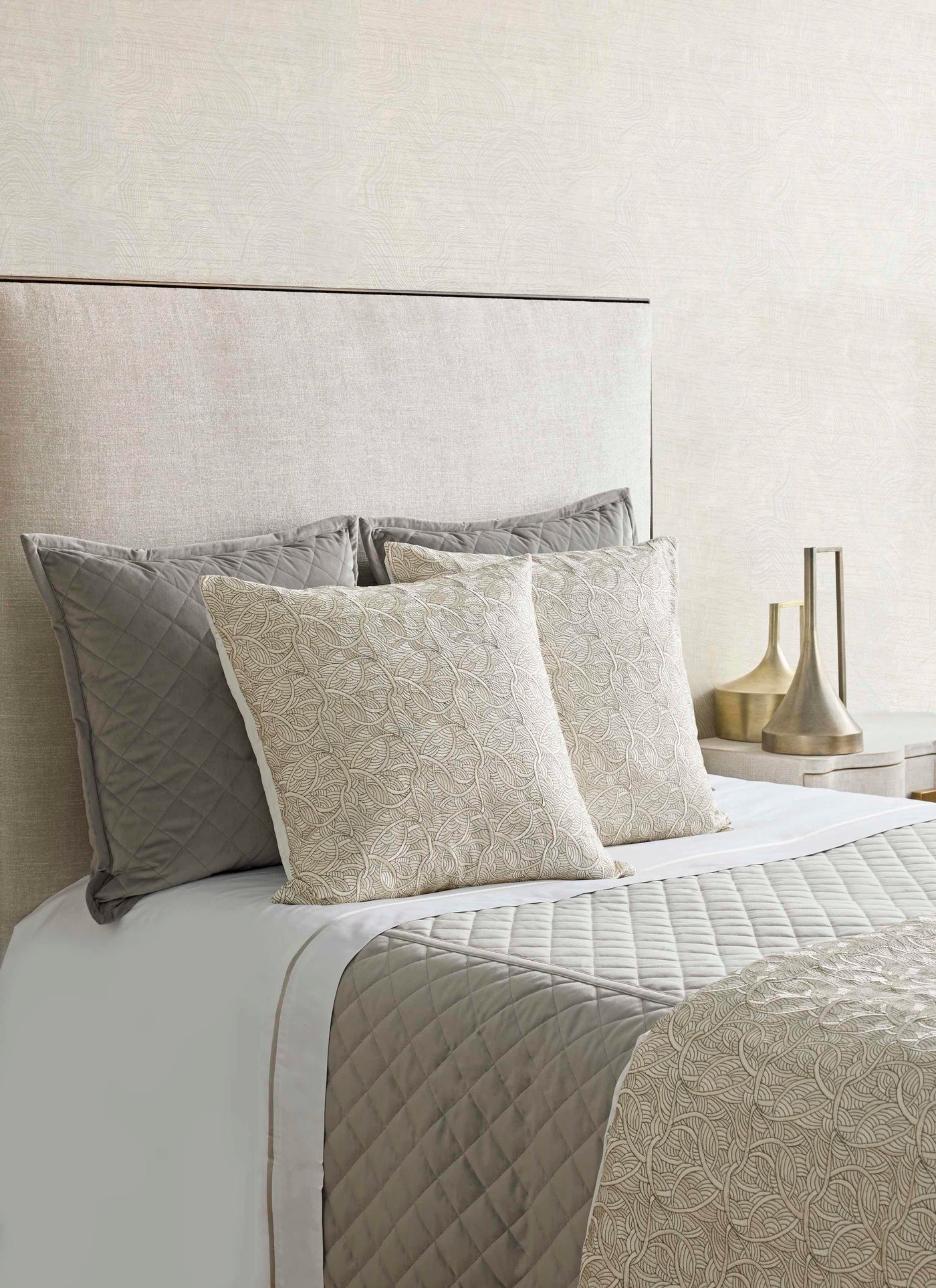 Taupe quilted velvet coverlet with ivory embroidered euro shams on a styled bed.