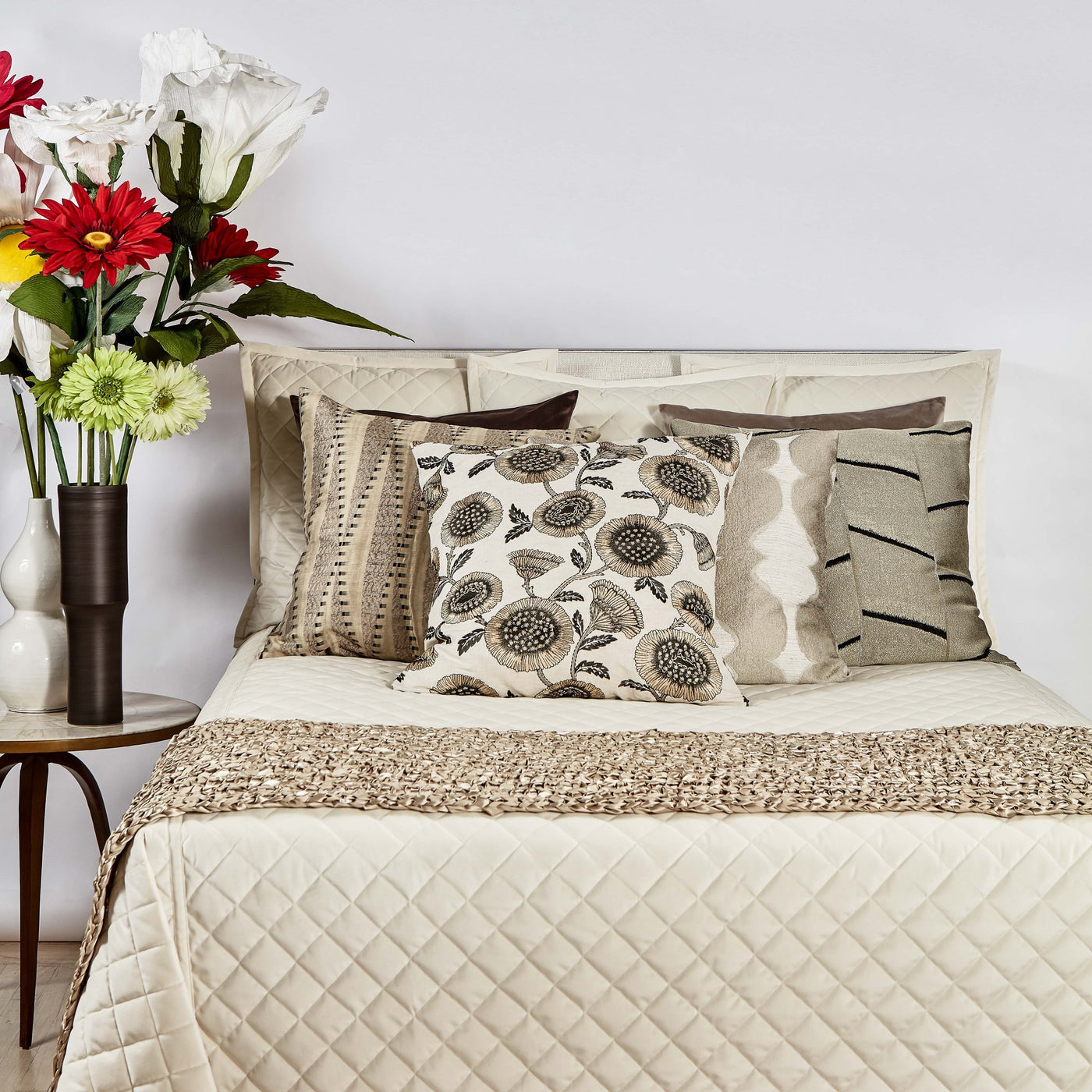 Ivory diamond-quilted velvet coverlet styled on bed with layered neutral decorative pillows.