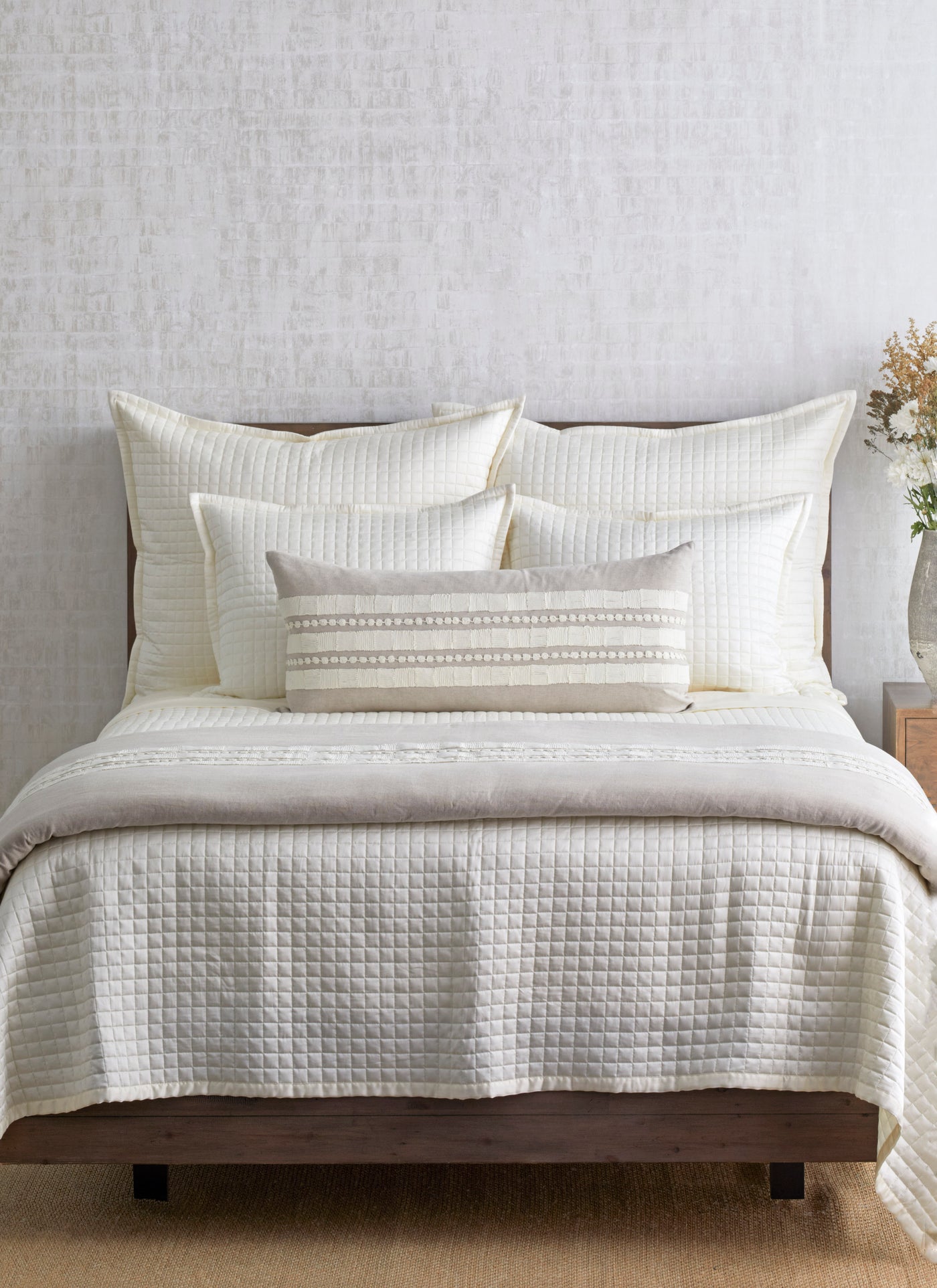 Ivory quilted coverlet styled on a made bed with layered pillows and neutral bedding.