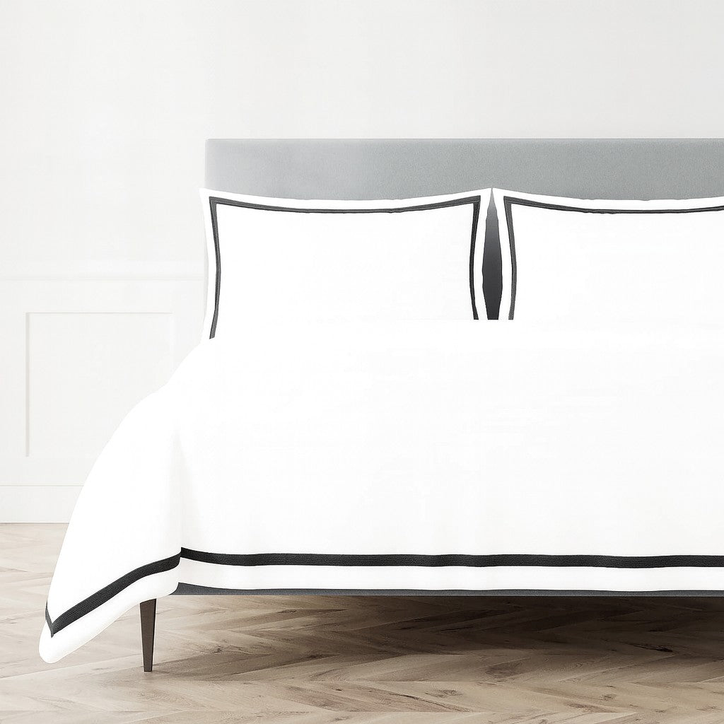 White Ann Gish duvet and shams with bold black border trim on a styled bed.