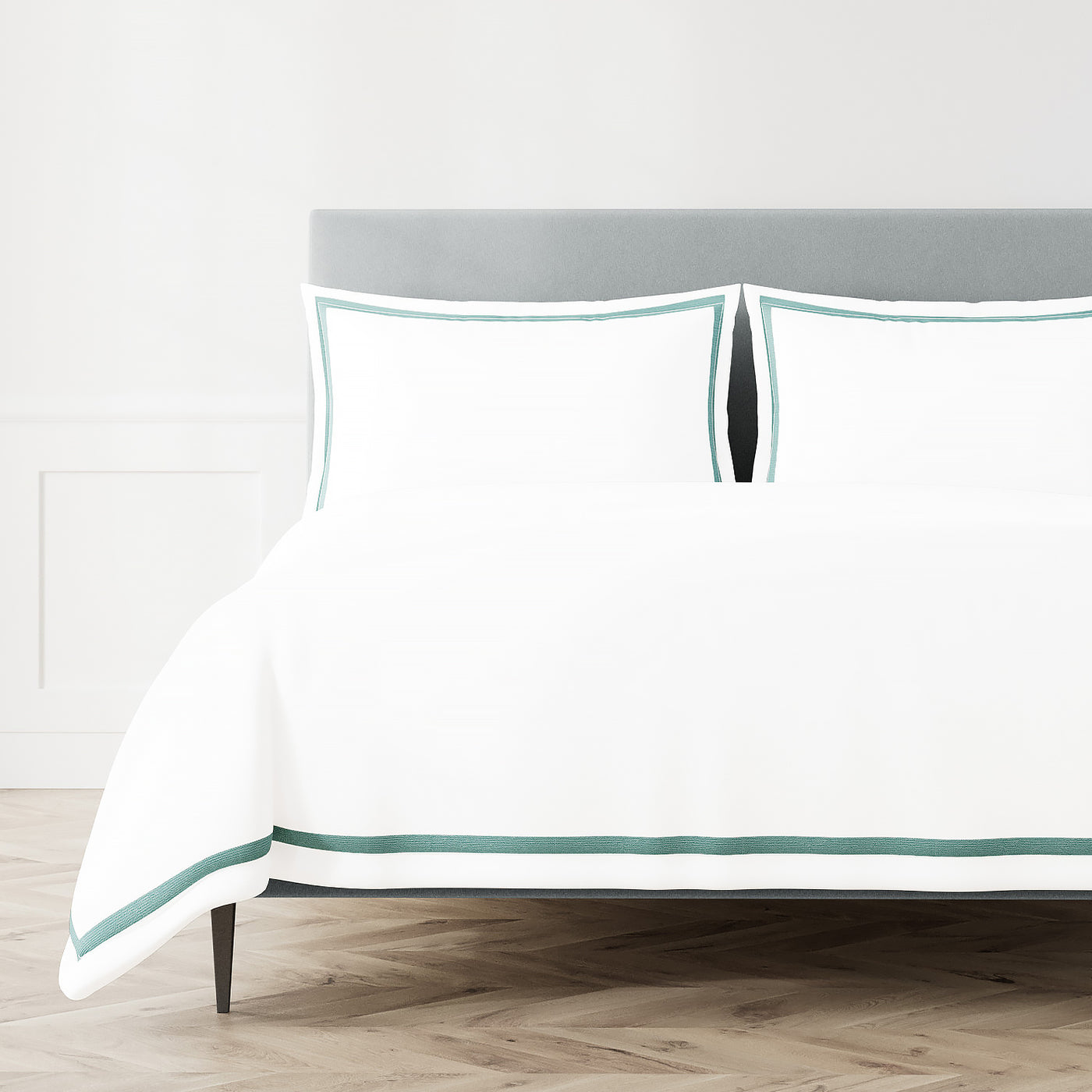White Ann Gish duvet cover with teal double-stripe trim, styled on a made bed with matching shams.