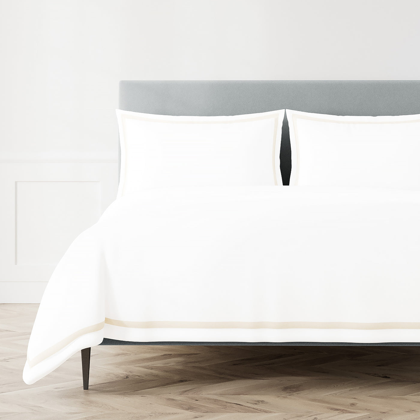 White Ann Gish duvet cover with champagne trim detail, styled on a bed with matching shams.