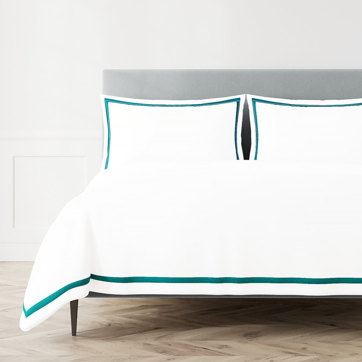 White Ann Gish duvet and pillowcases with teal trim border on a styled bed.