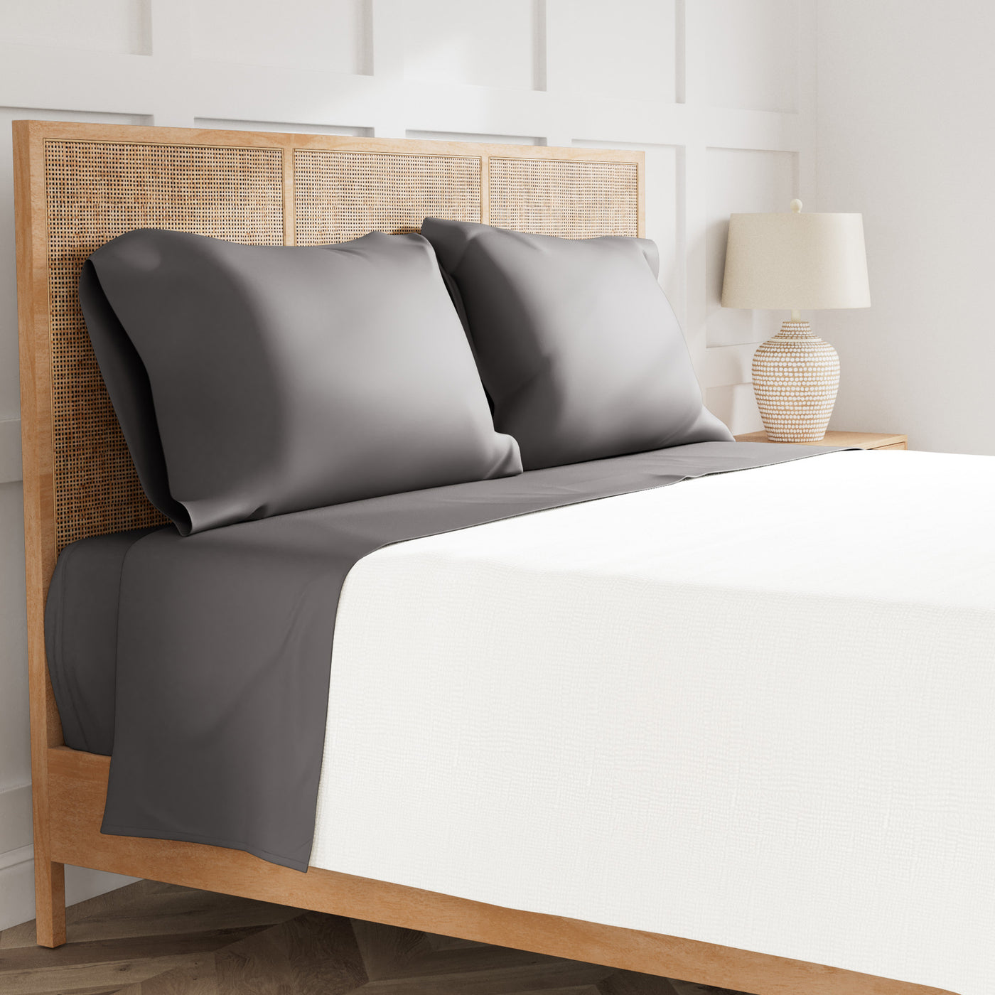 Charcoal flat sheet and pillowcases styled on a rattan bed with white duvet.