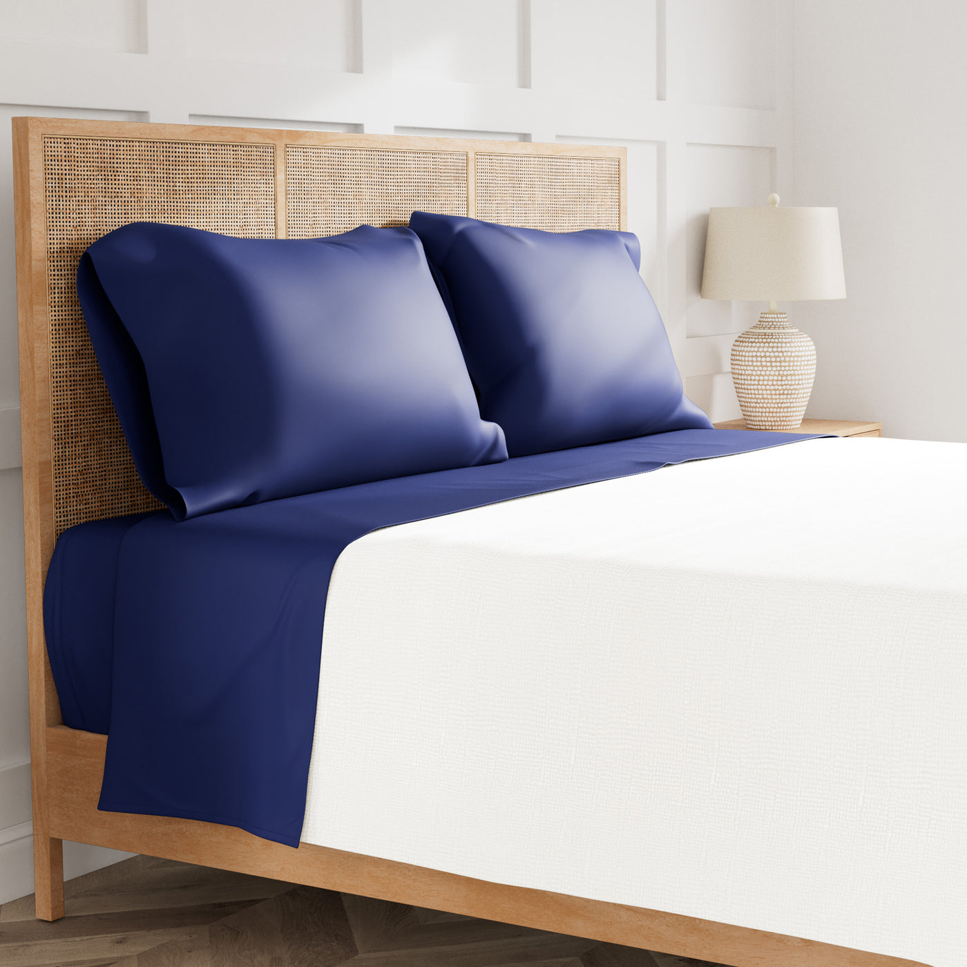 Navy and white Ann Gish Ready-to-Bed 2.0 sheet set on rattan bed, bedroom styling.