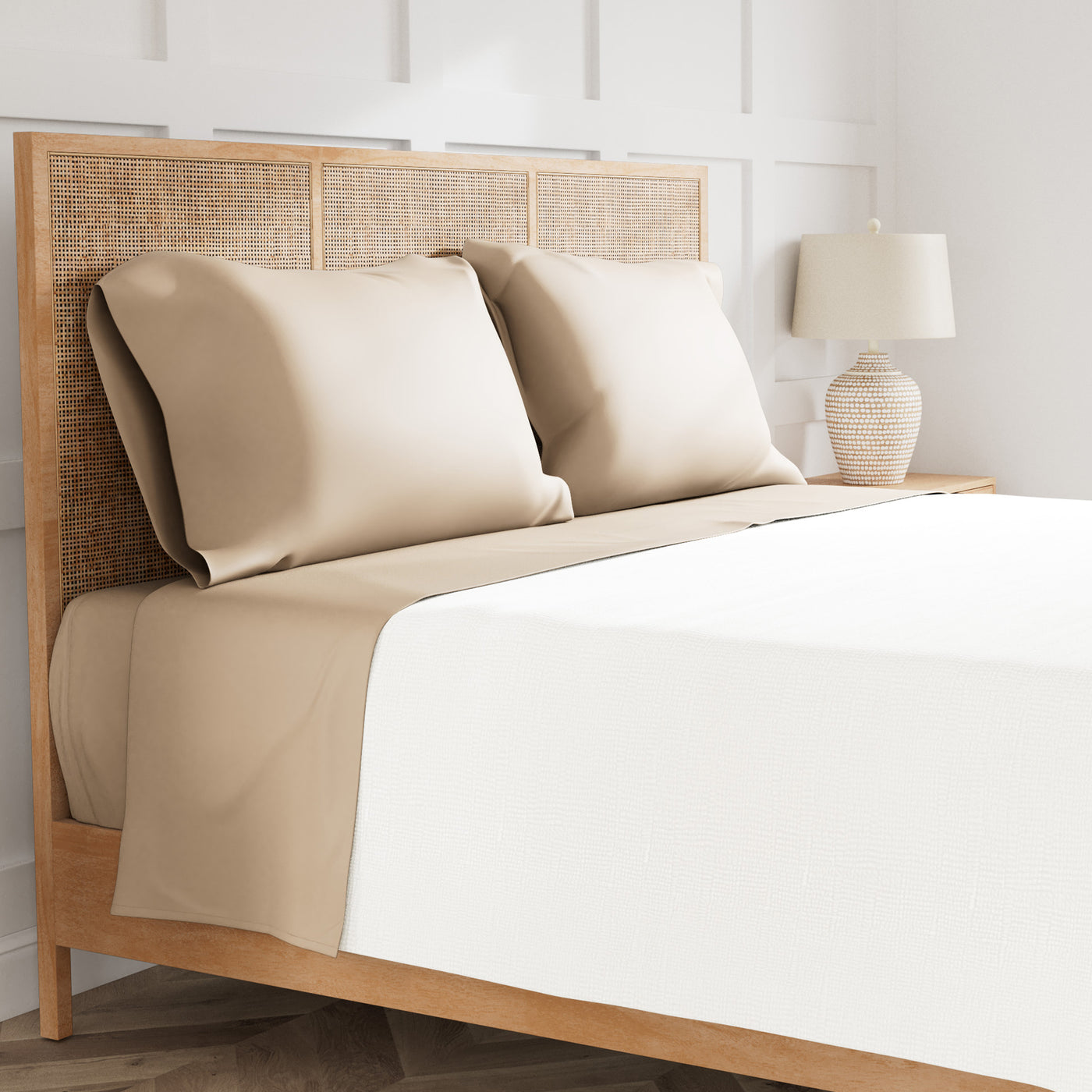 Taupe pillowcases and flat sheet with ivory duvet on a rattan bed frame.