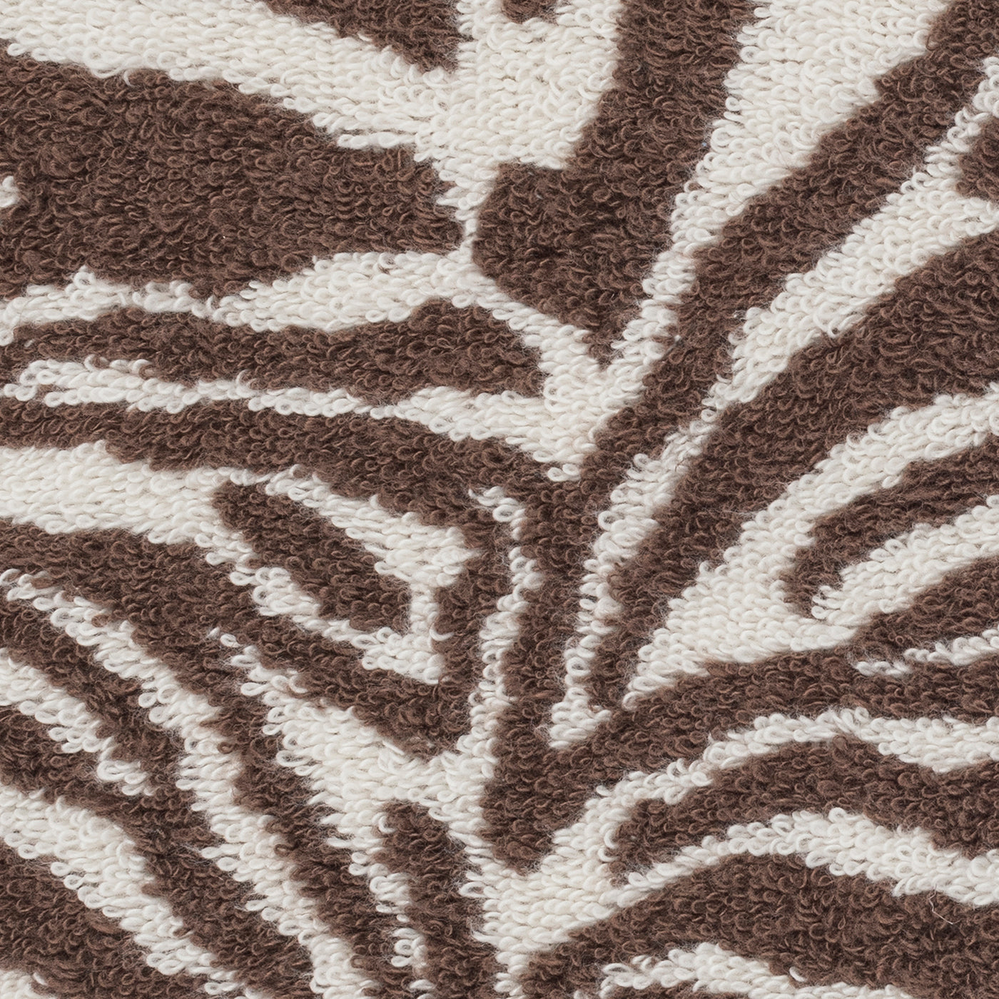 Close-up of the Regine Guest Towel by Matouk, featuring a textured linen-cotton blend with a brown and white abstract zebra jacquard pattern.