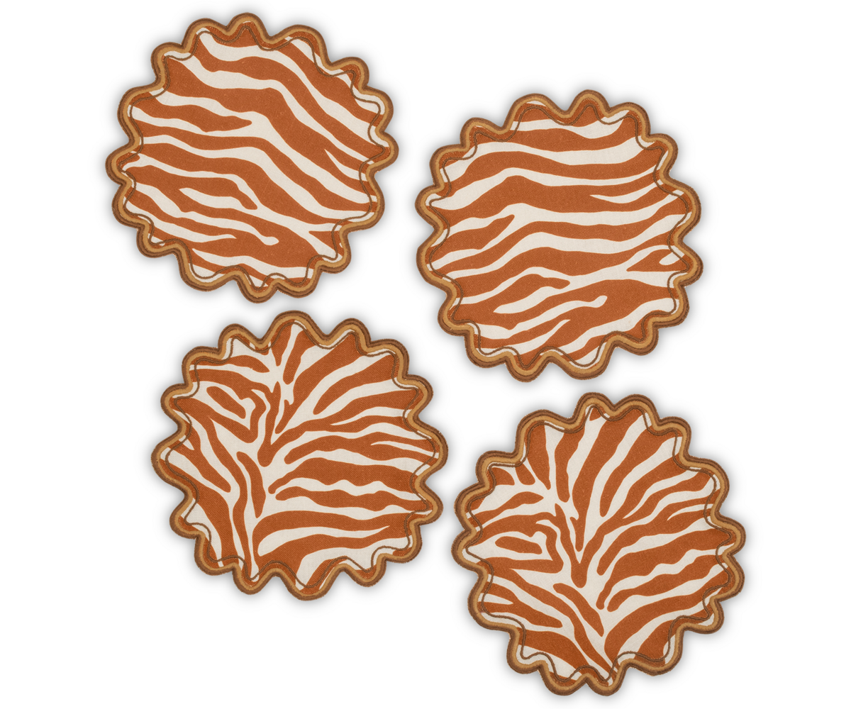 Four Regine cocktail napkins from Matouk, featuring a stylized zebra motif in orange and white, are arranged on a white background.