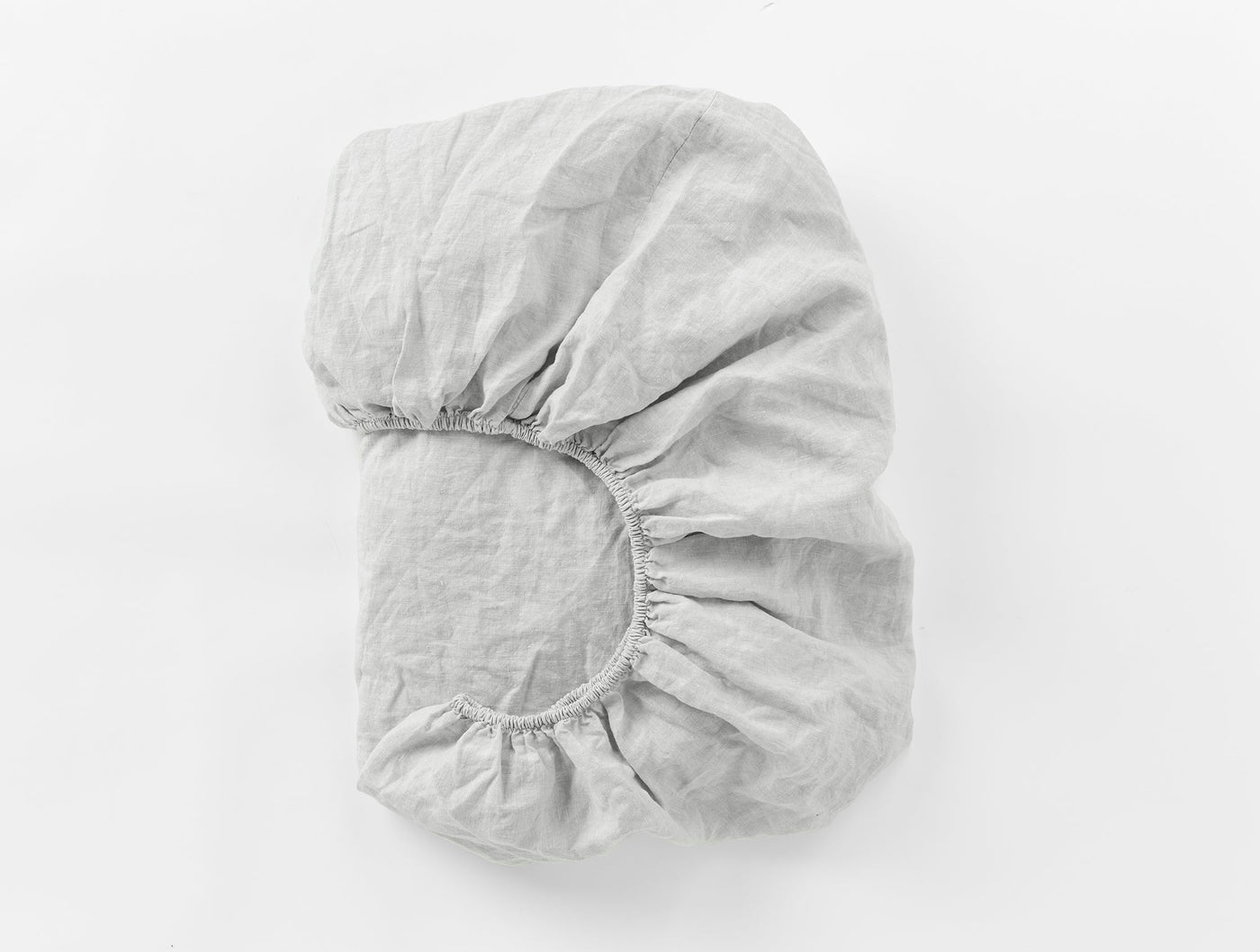 Folded silver Coyuchi Relaxed Linen fitted sheet showing elasticized corner detail.