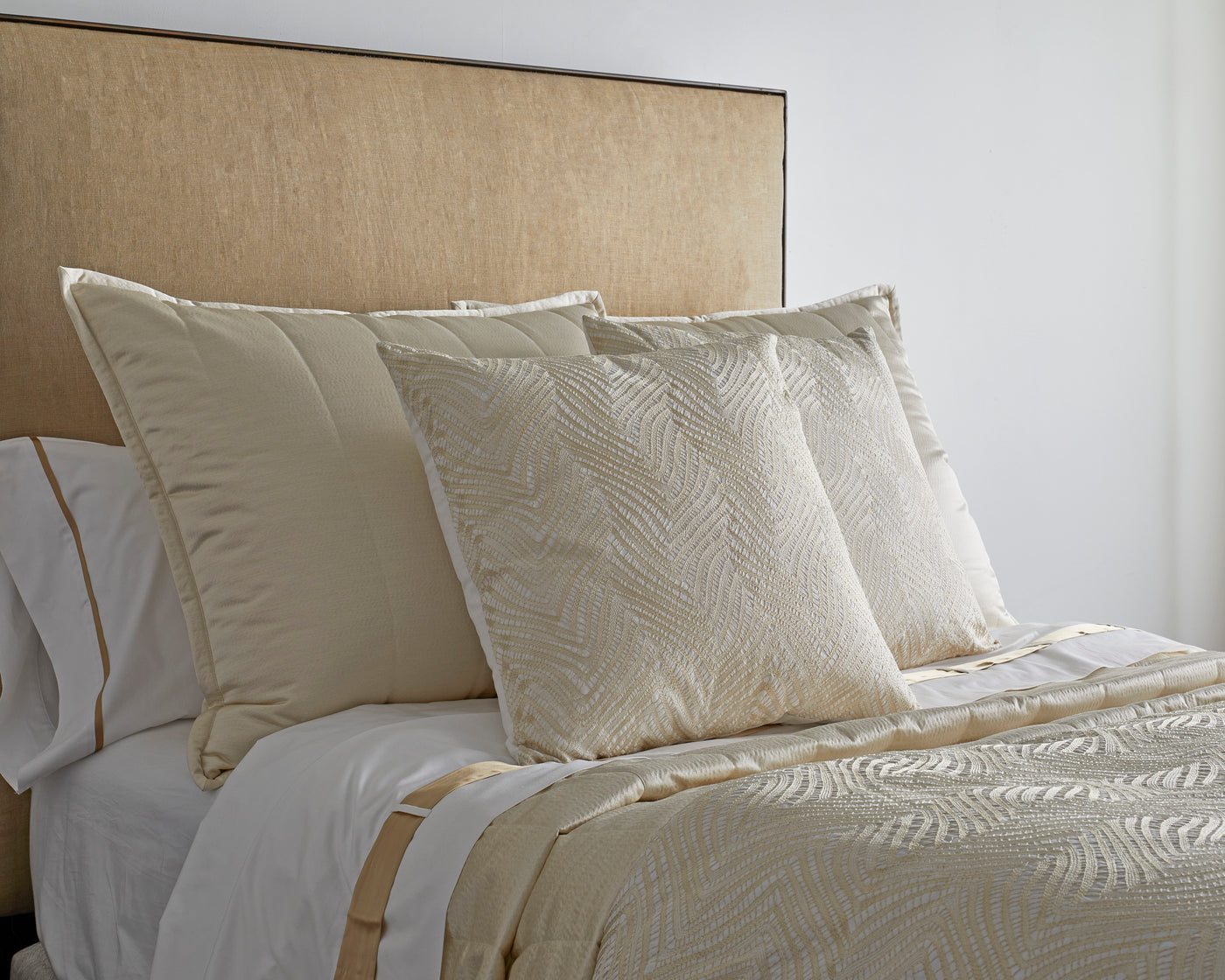 Champagne textured euro pillows with woven leaf pattern styled against neutral bedding.