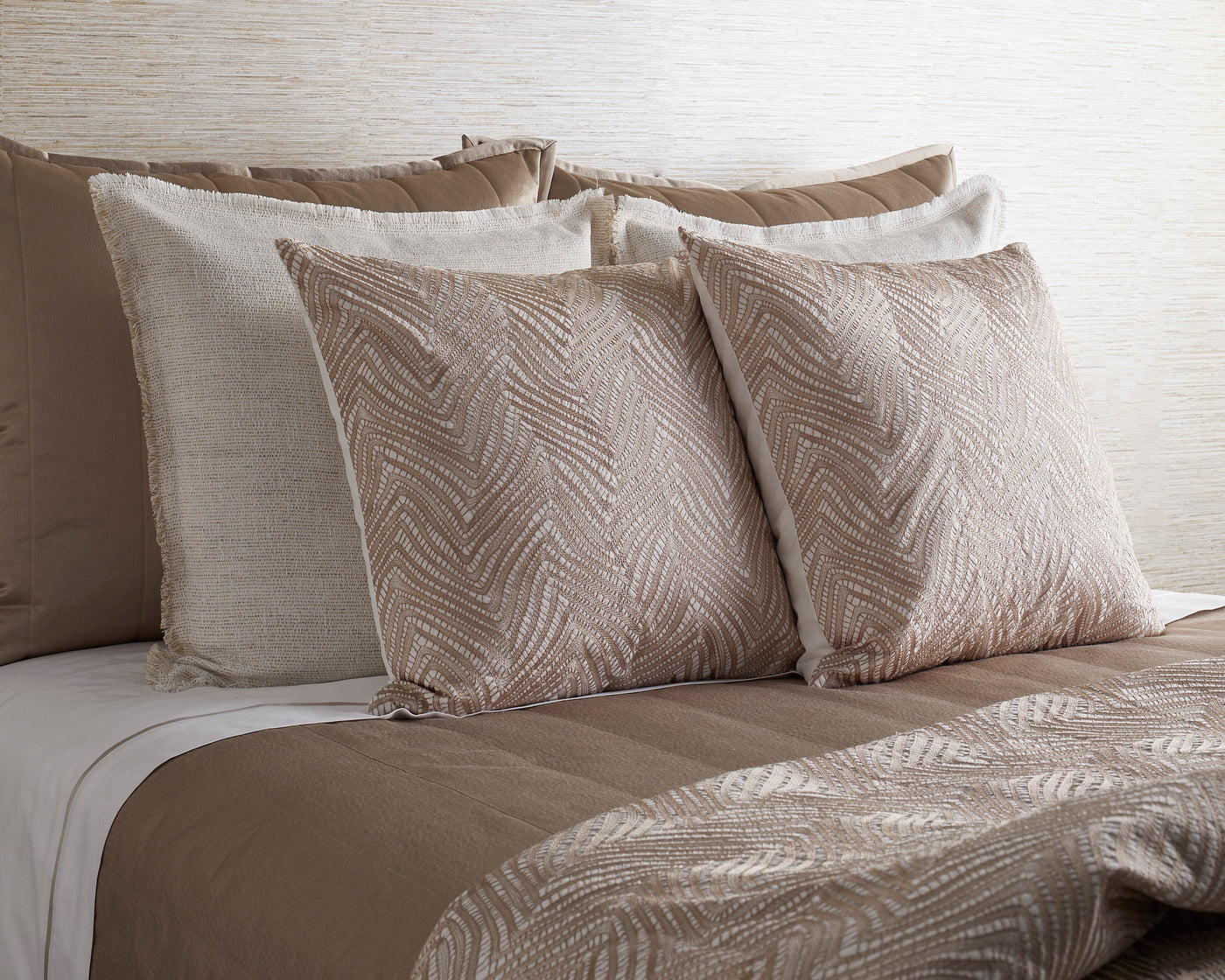 Ann Gish Retortoli pillows in champagne, chevron texture, styled on a neutral bedding arrangement.