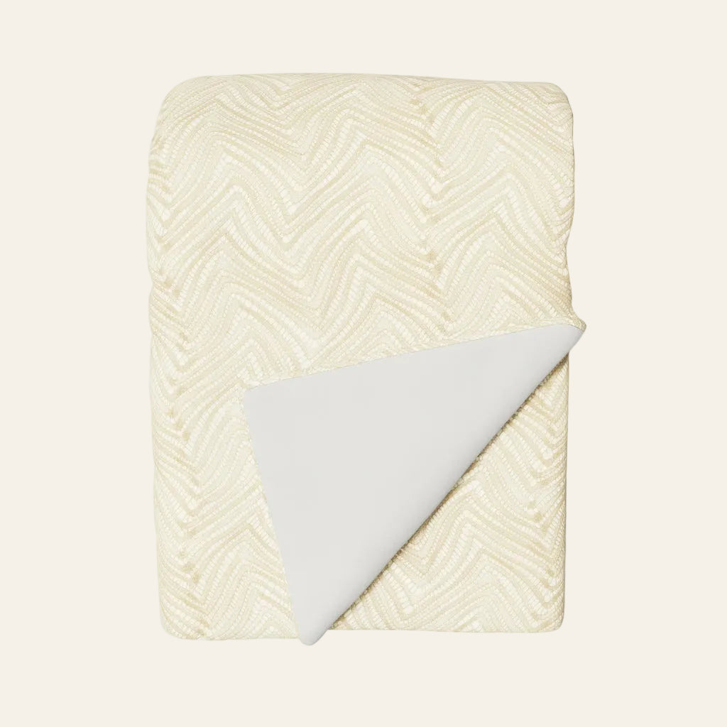 Ann Gish Retortoli throw in ivory, folded with corner turned to reveal white reverse.