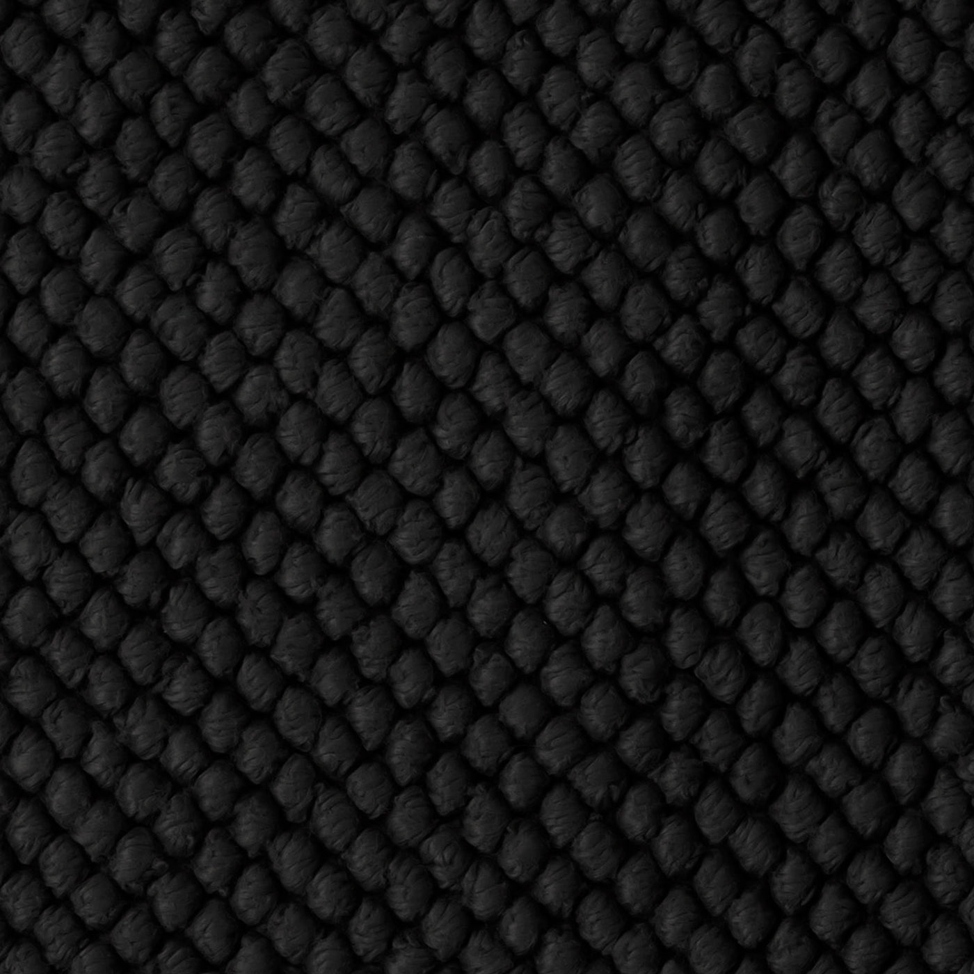 Close-up of Matouk Reverie bath rug in black showing textured waffle weave pattern.