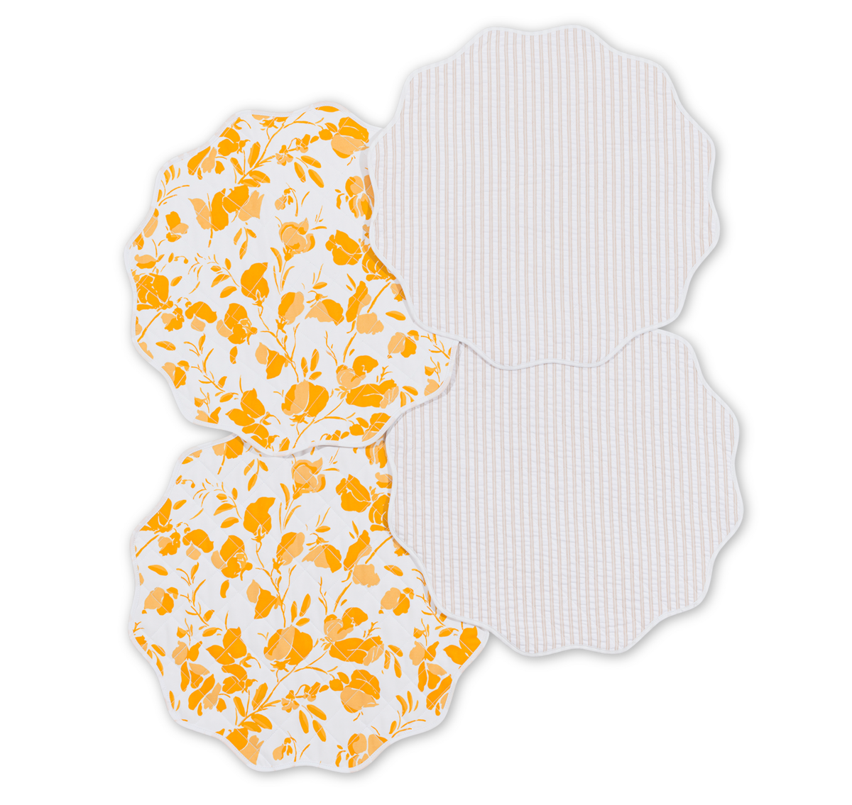The Matouk Quilted Reversible Placemat Set includes four placemats with scalloped edges: two have a yellow floral pattern and two feature light gray stripes, ideal for adding a cheerful touch to your dining table.
