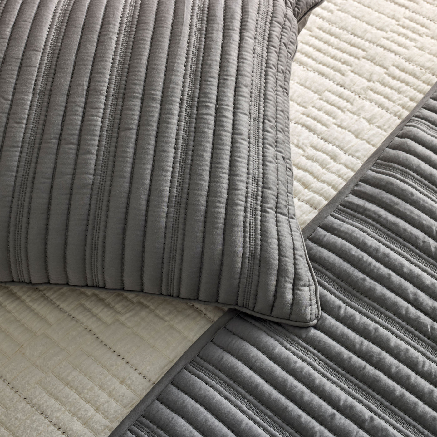 Close-up of Ann Gish Rib coverlet set in charcoal, showing quilted ribbed texture on pillow and coverlet.