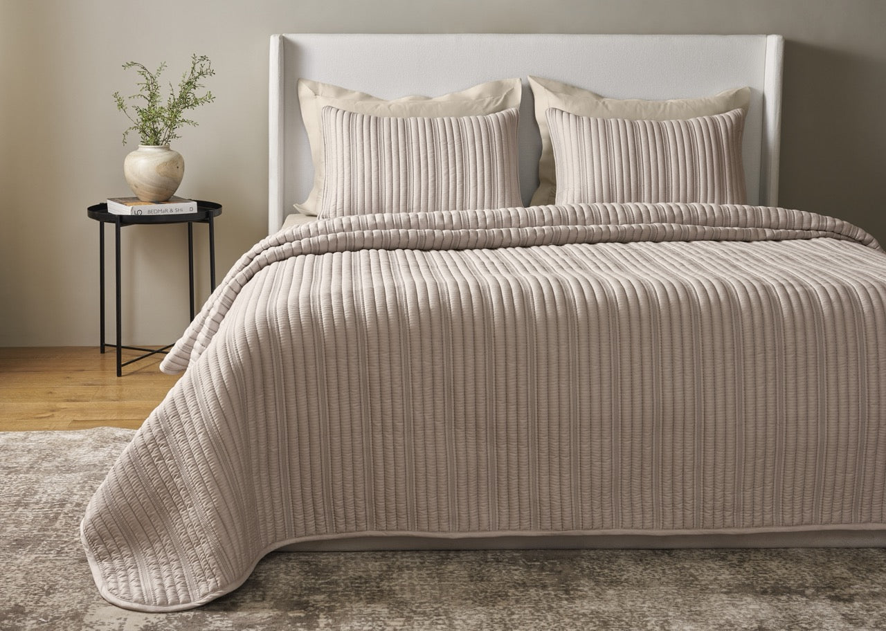 Ann Gish Rib coverlet set in taupe, styled on bed showing full drape and ribbed texture.