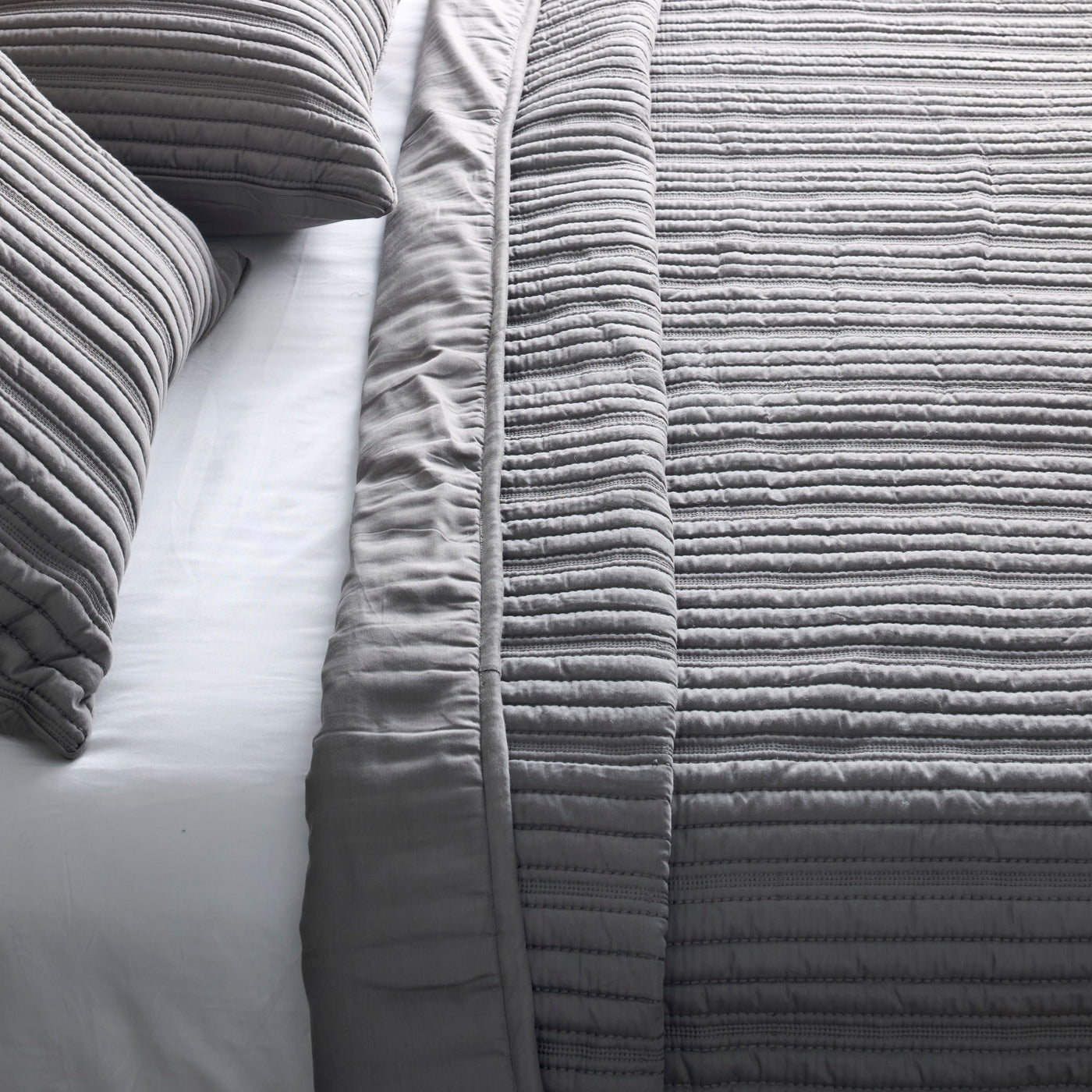 Close-up of Ann Gish Rib coverlet in grey, showing horizontal ruched texture and border detail.
