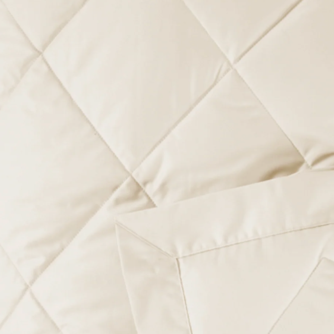 Close-up of ivory quilted cotton shell with diagonal stitching detail.
