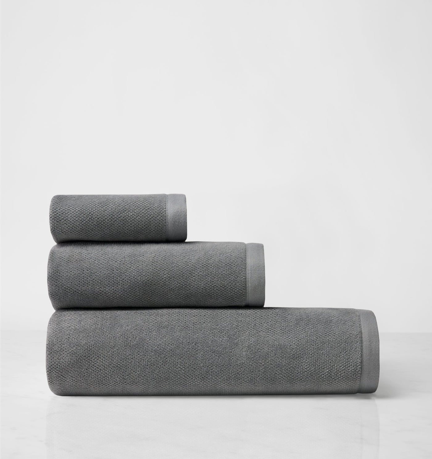 Close-up of three rolled slate grey towels stacked in graduated sizes.
