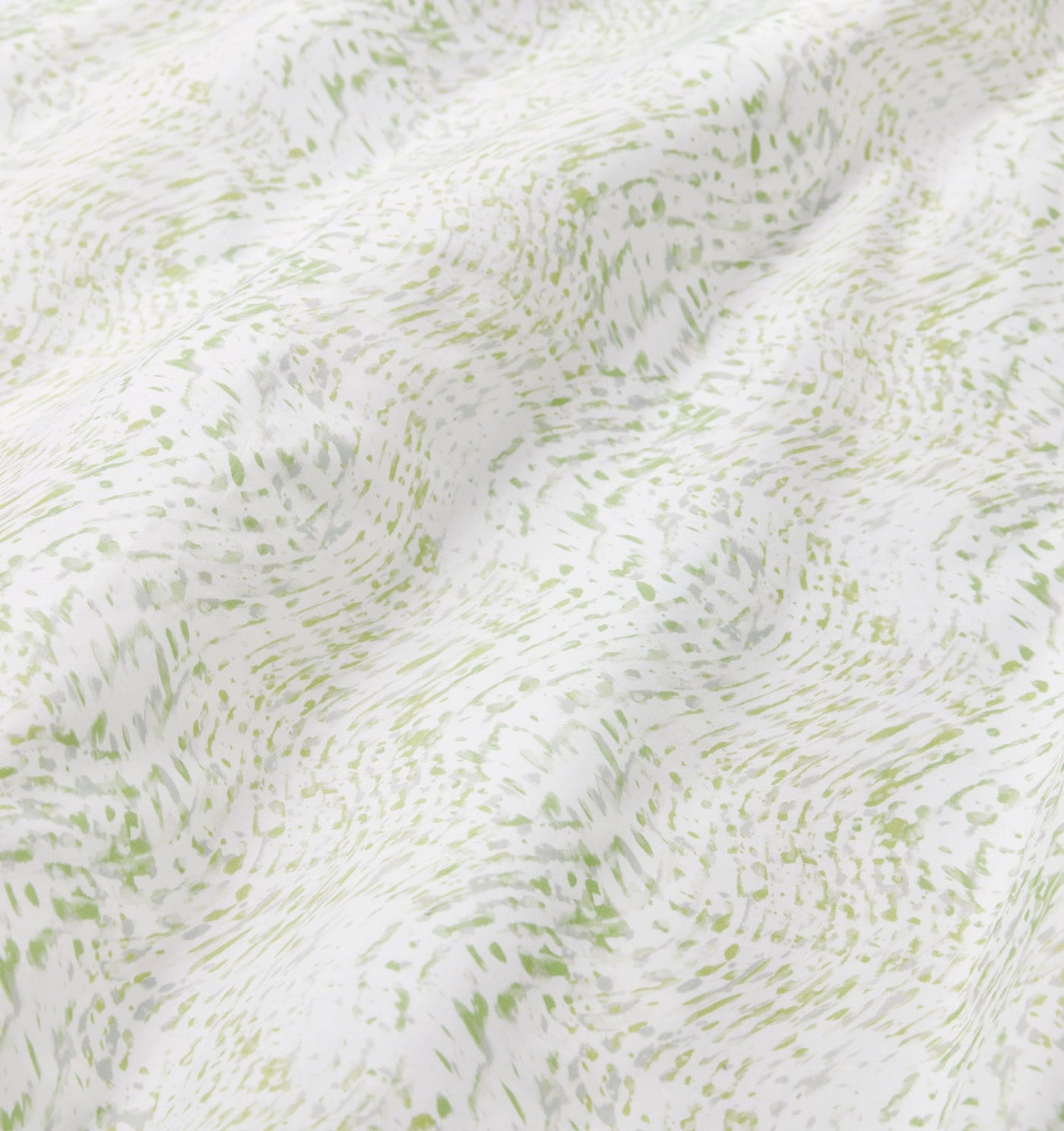 Close-up of Sferra Meloria fabric showing sage green speckled pattern on white cotton.