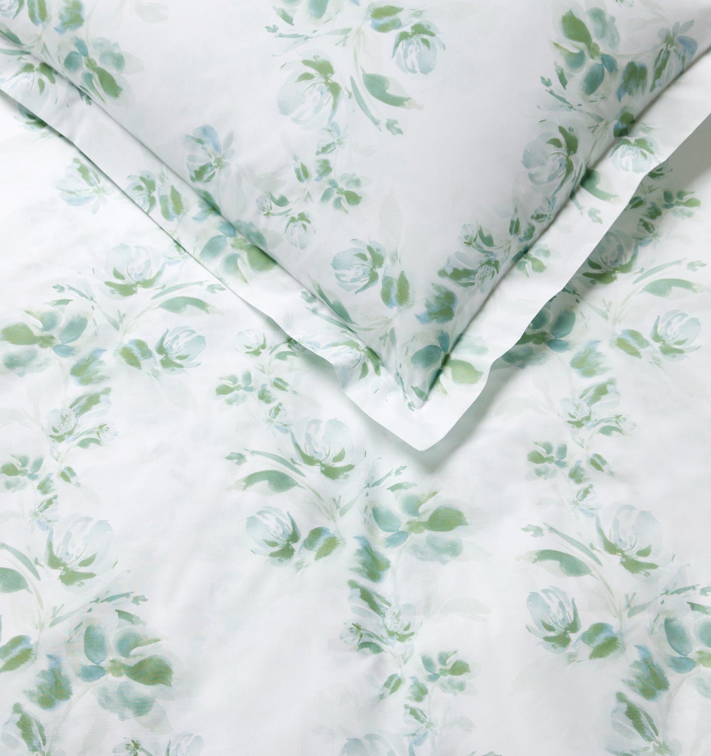 Close-up of Sferra Rosa duvet cover corner with sage and aqua watercolor floral print on white.