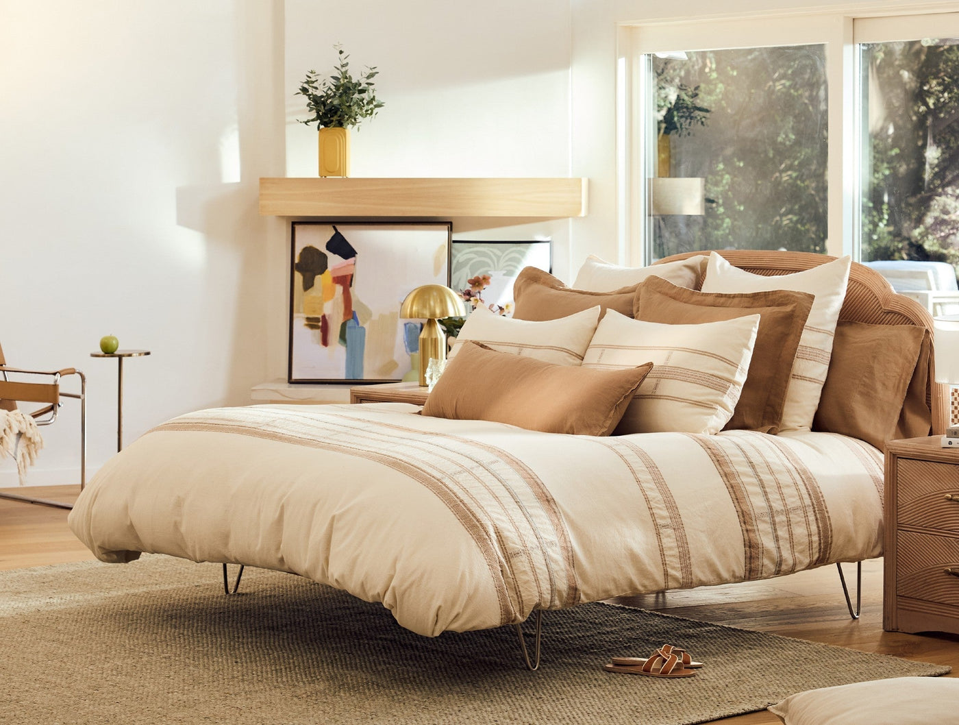 Coyuchi Bodega Bay duvet cover styled on bed with tan stripe detail and layered ivory and camel pillows.