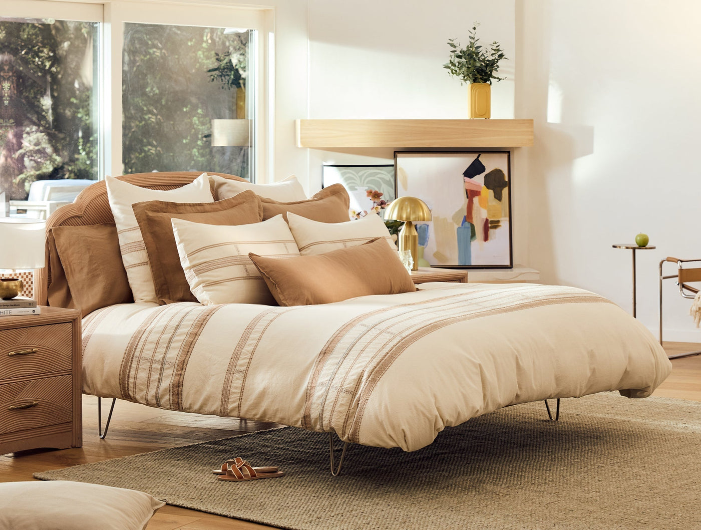 Ivory and caramel striped shams styled on a made bed with layered neutral bedding.