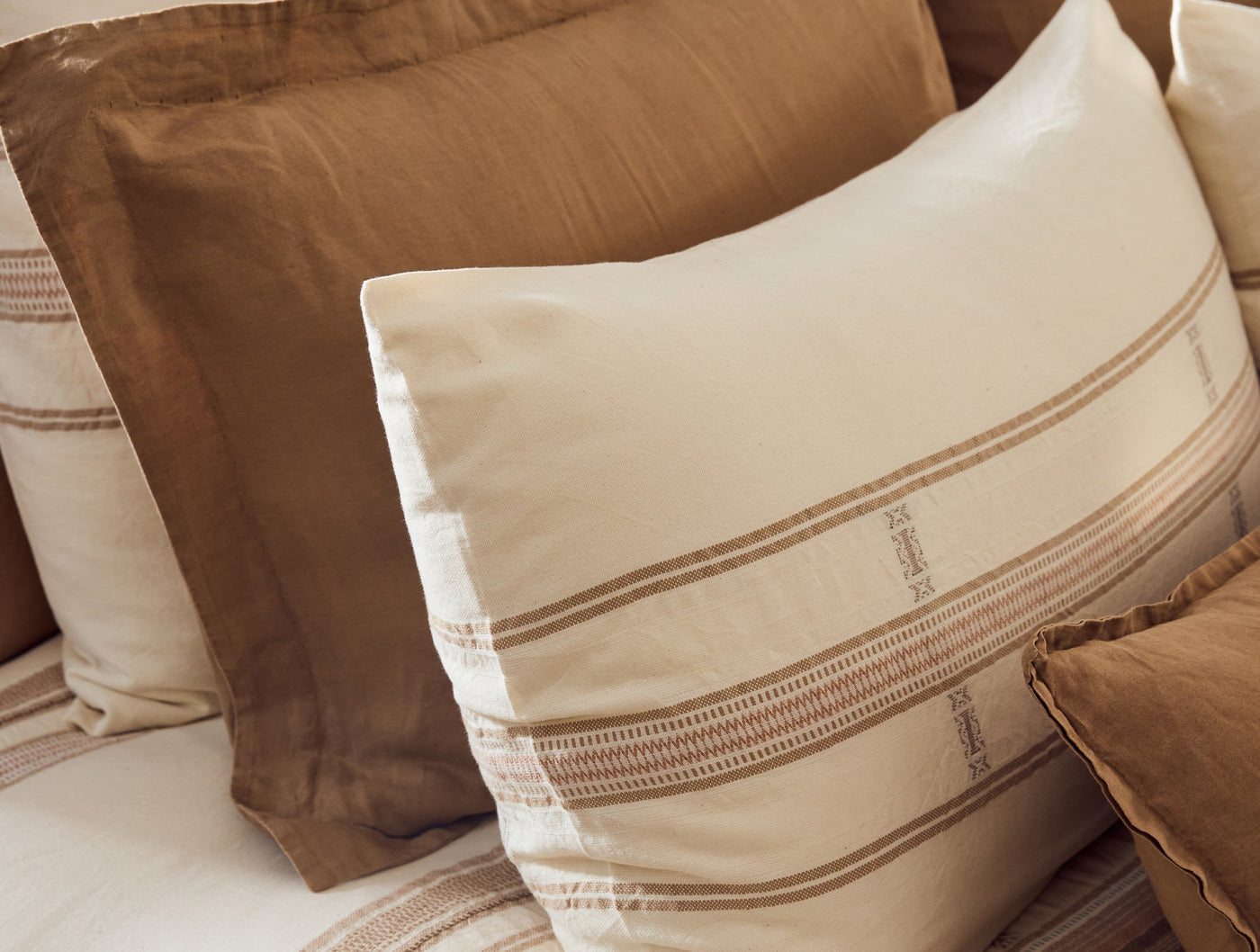 Coyuchi Bodega Bay pillow sham in ivory with tan woven stripe border detail.