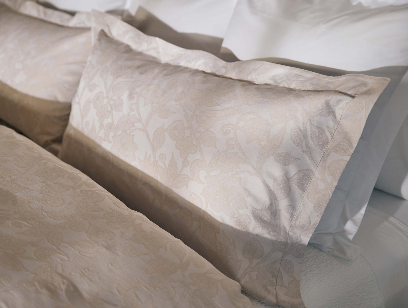 Close-up of Coyuchi Heritage Percale Jacquard sham in champagne with floral damask weave detail.