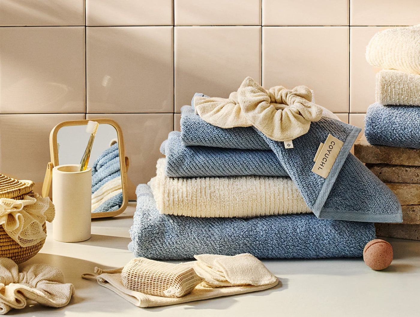 Coyuchi Bare makeup pads and wash bag styled in a bathroom with blue and ivory towels.