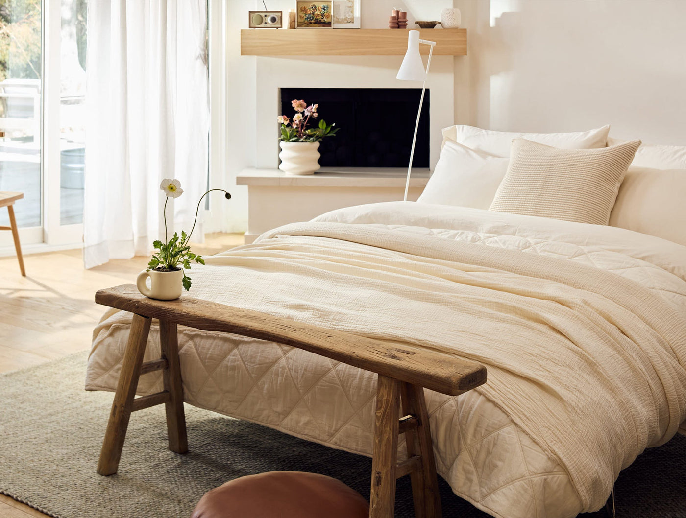 Ivory crinkled percale duvet set on bed, rustic wood bench and bright airy room.