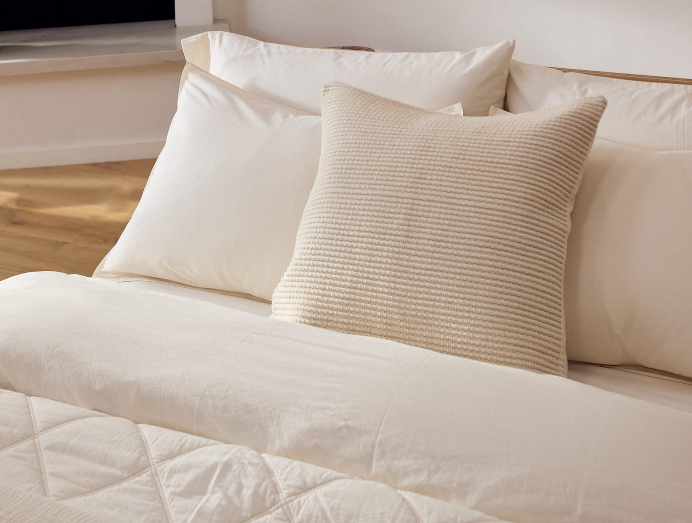 Ivory duvet set styled with a textured sand euro pillow on a wood-framed bed.