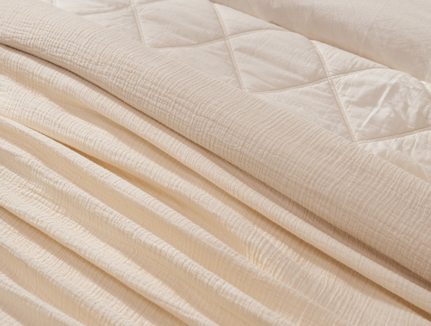 Close-up of ivory matelassé throw with diamond quilting detail and ribbed texture.