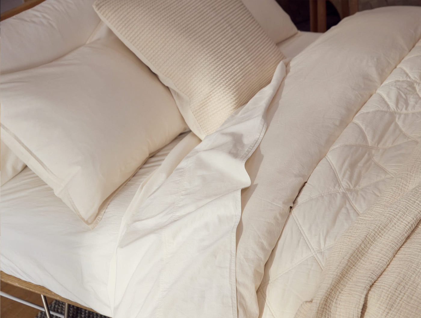 Ivory crinkled percale sheets styled on a bed with a quilted duvet and ribbed pillow.