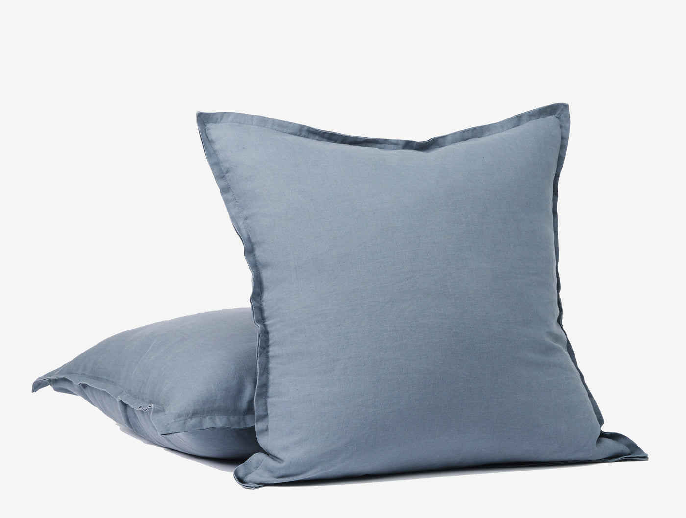 Close-up of two stacked slate blue Coyuchi Relaxed Linen pillowcases with flanged edges.