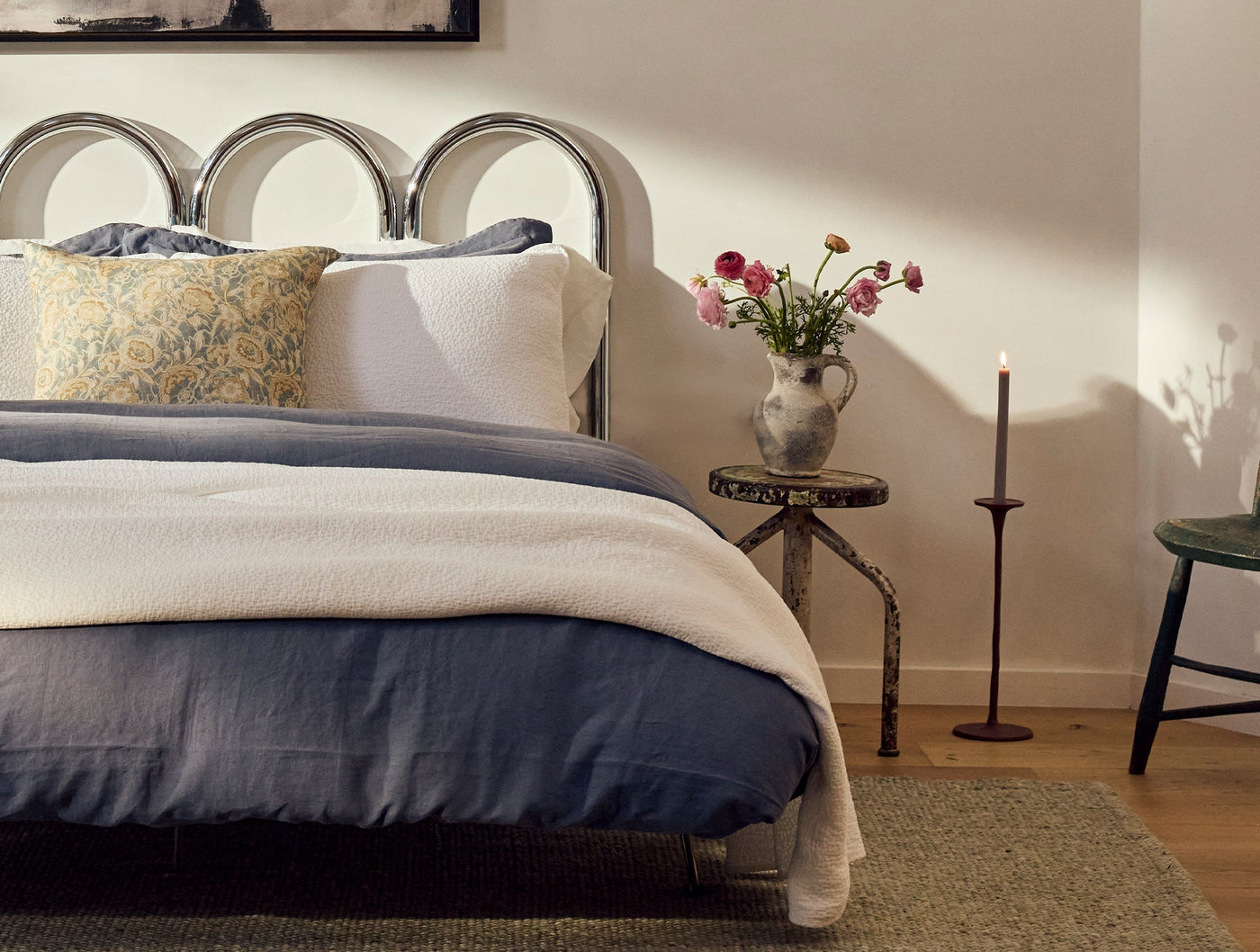 Balboa Print pillow styled on bed with navy linen bedding and floral accent.