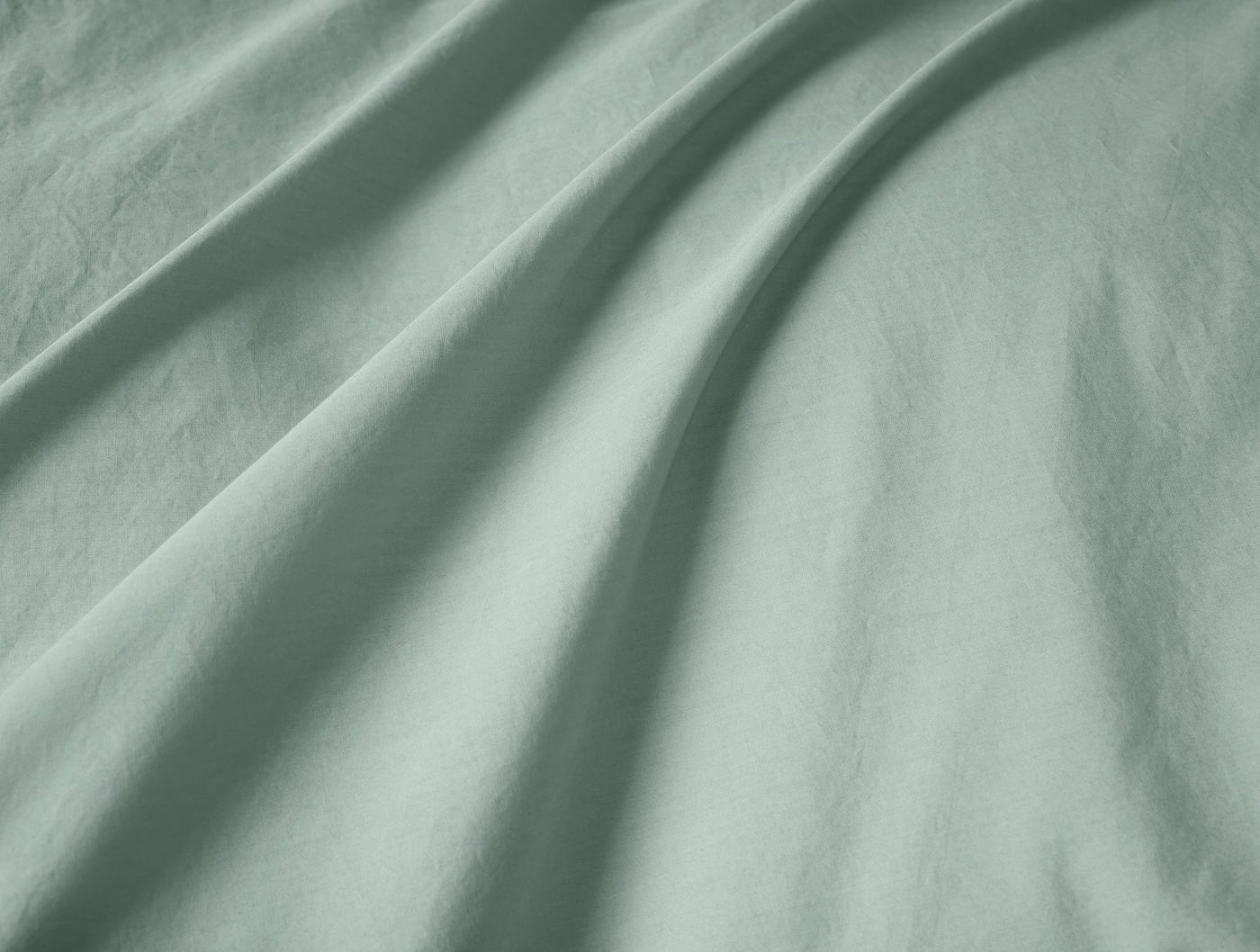 Soft folds of sage green percale fabric showing smooth texture and drape.