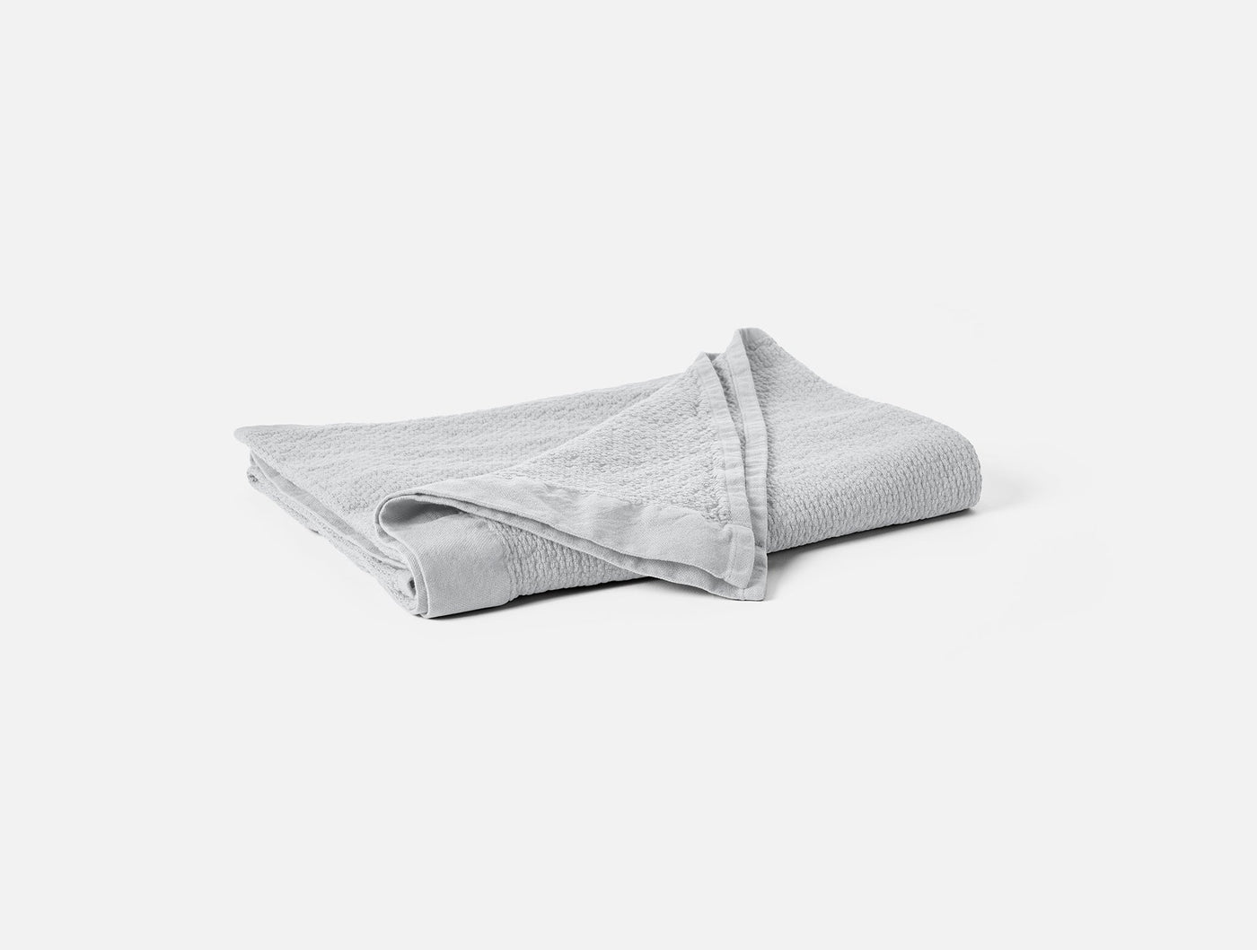 Folded silver Coyuchi Adriatic bath sheet showing textured weave and border detail.
