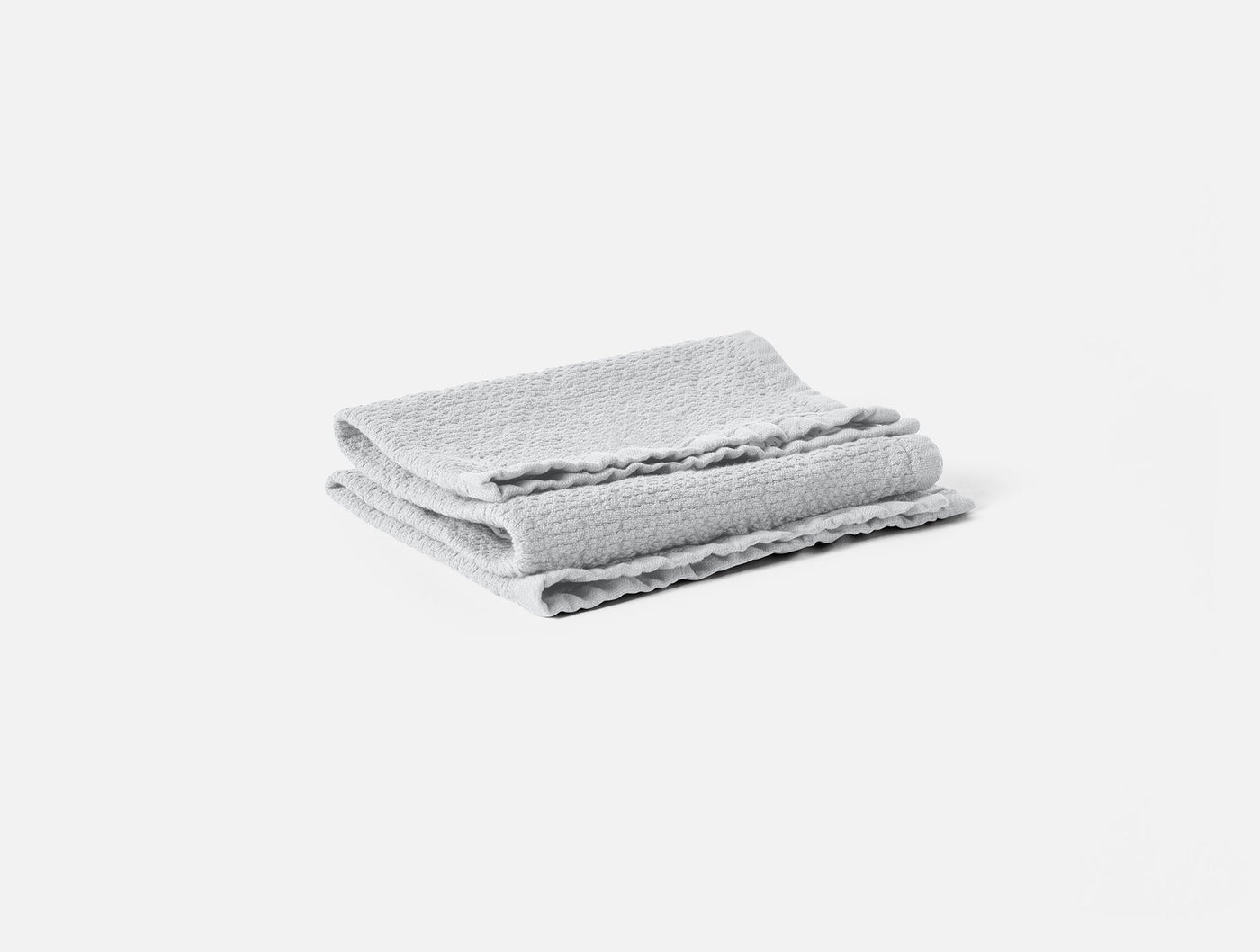 Folded light grey waffle-textured washcloth with frayed hem detail, shown from above.
