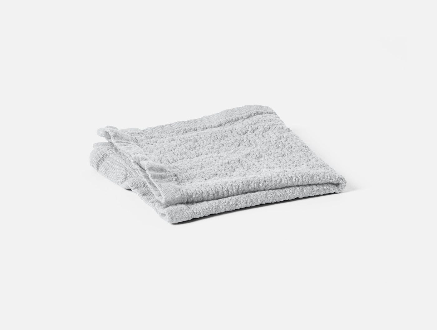 Folded light grey terry washcloth with ridged texture on white background.